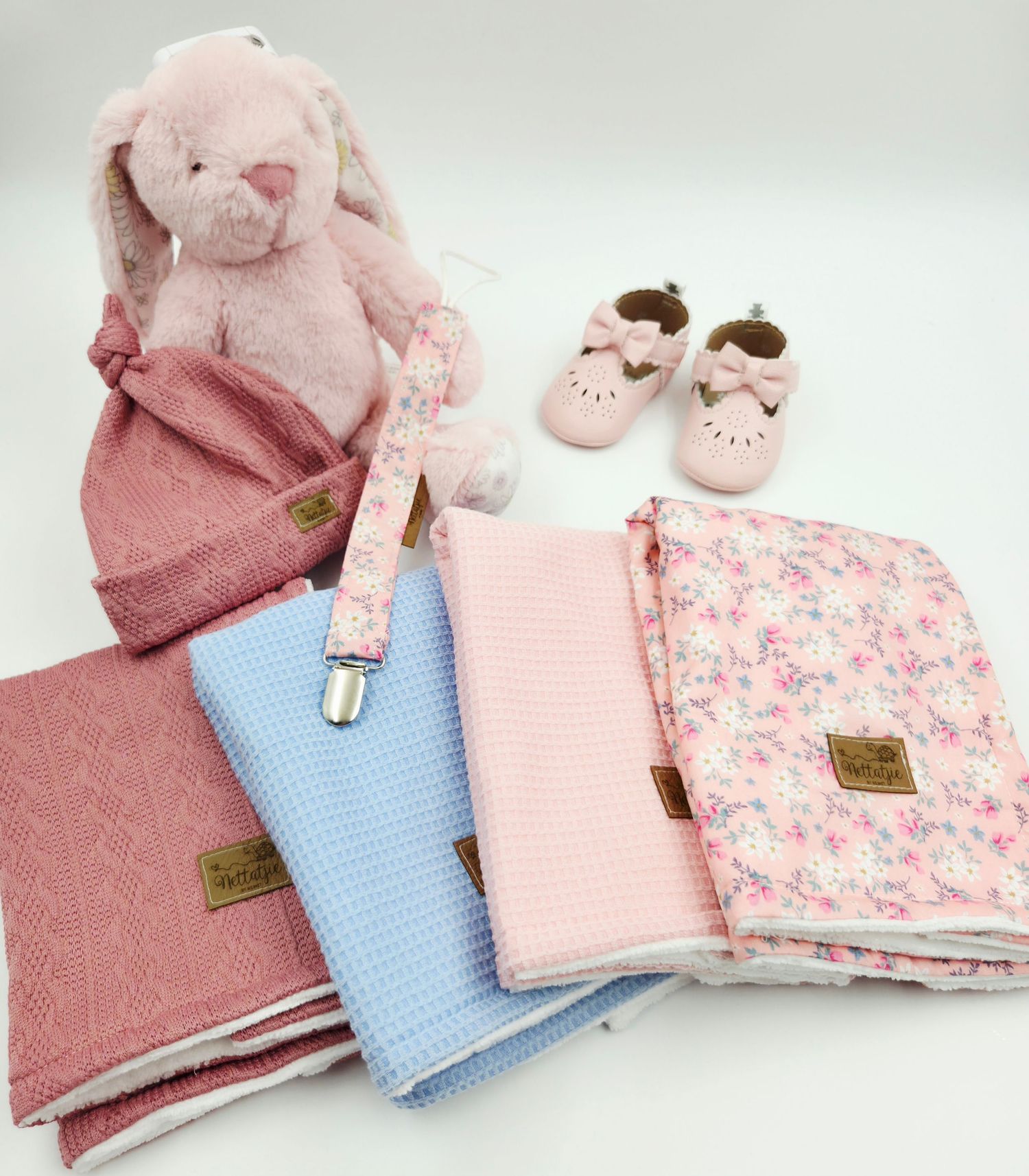 Pink plush bunny with matching baby blankets, shoes, and accessories in pastel colors.