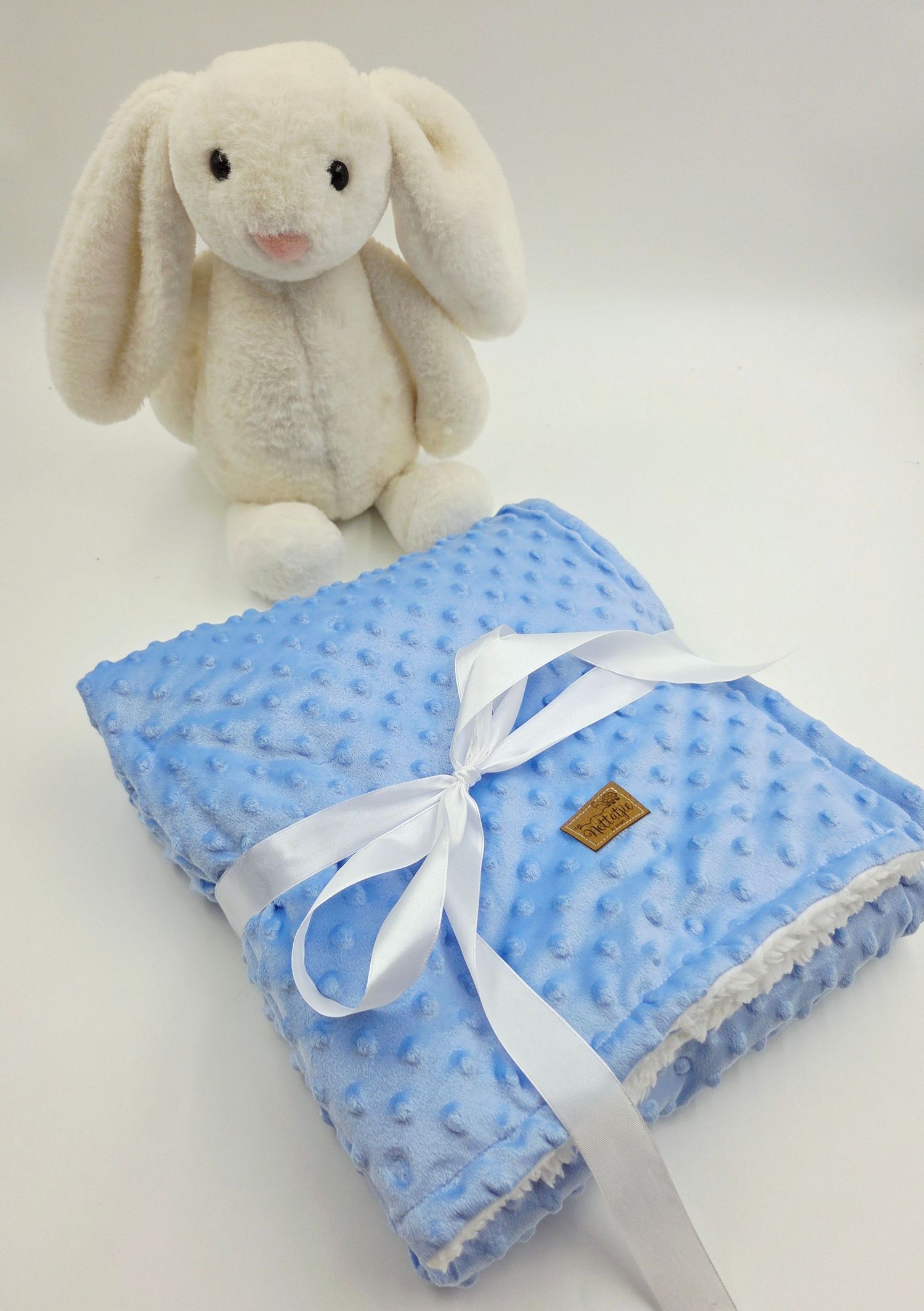 White plush bunny with soft blue minky blanket tied with white ribbon.