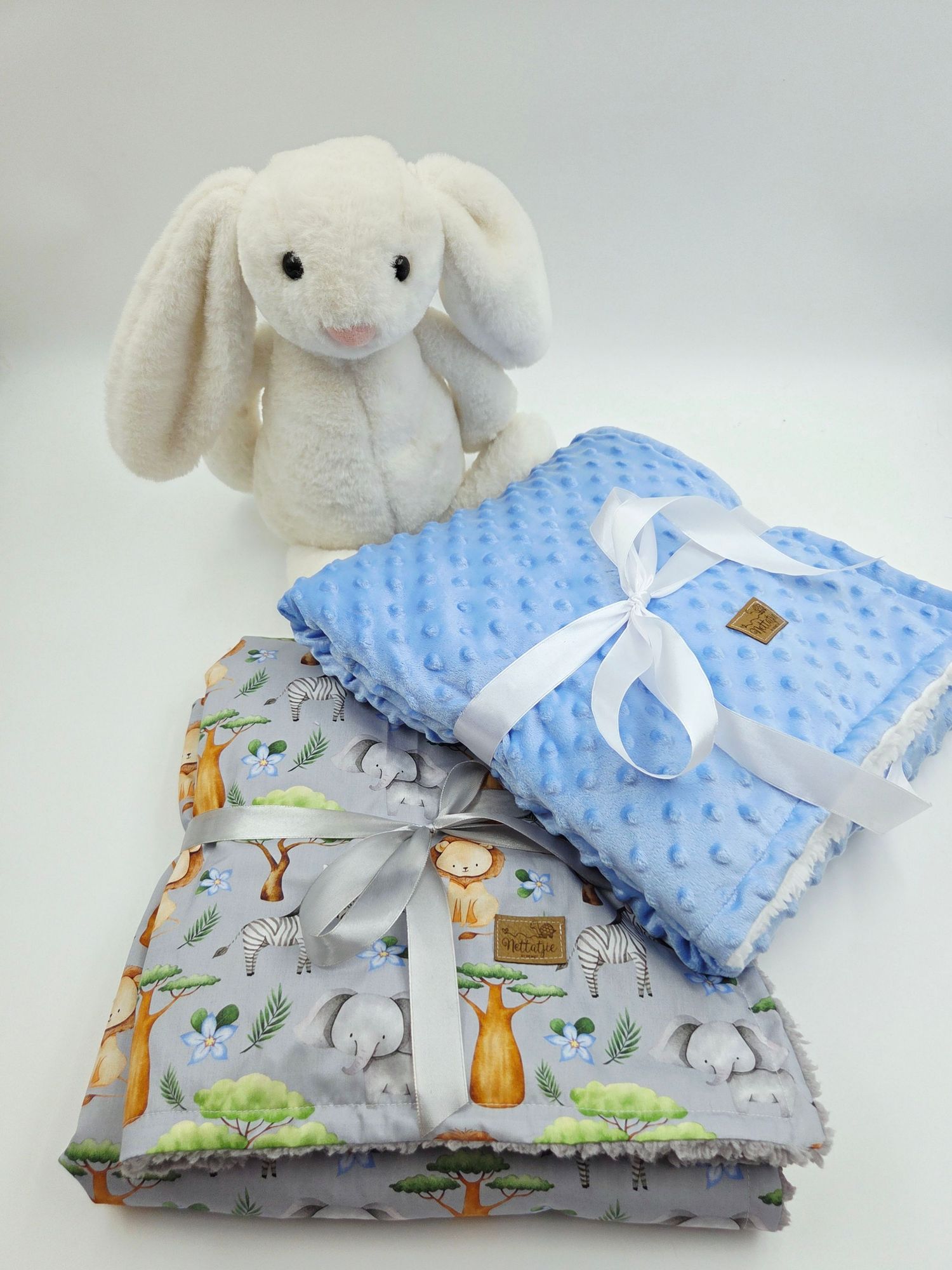 White plush bunny with blue minky blanket and woodland animal print baby blanket.