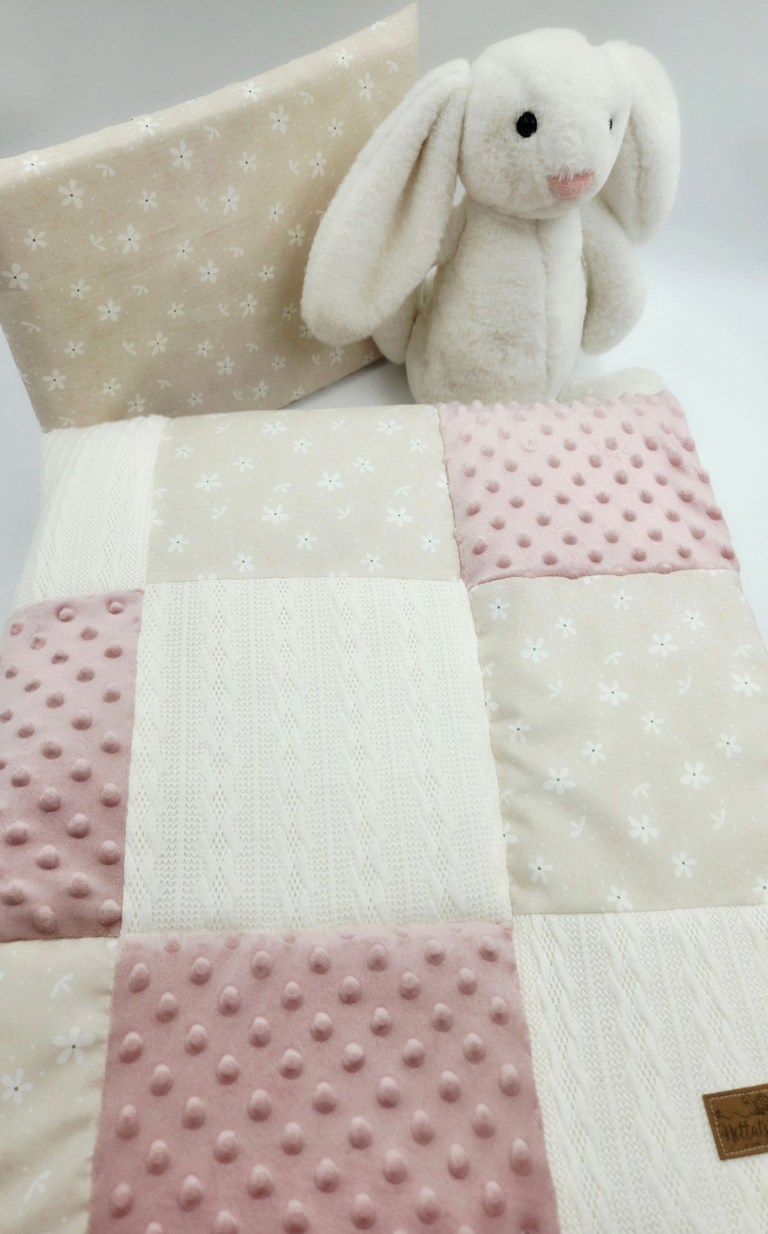 Plush white bunny toy with pink minky blanket featuring star pattern and textured dots.