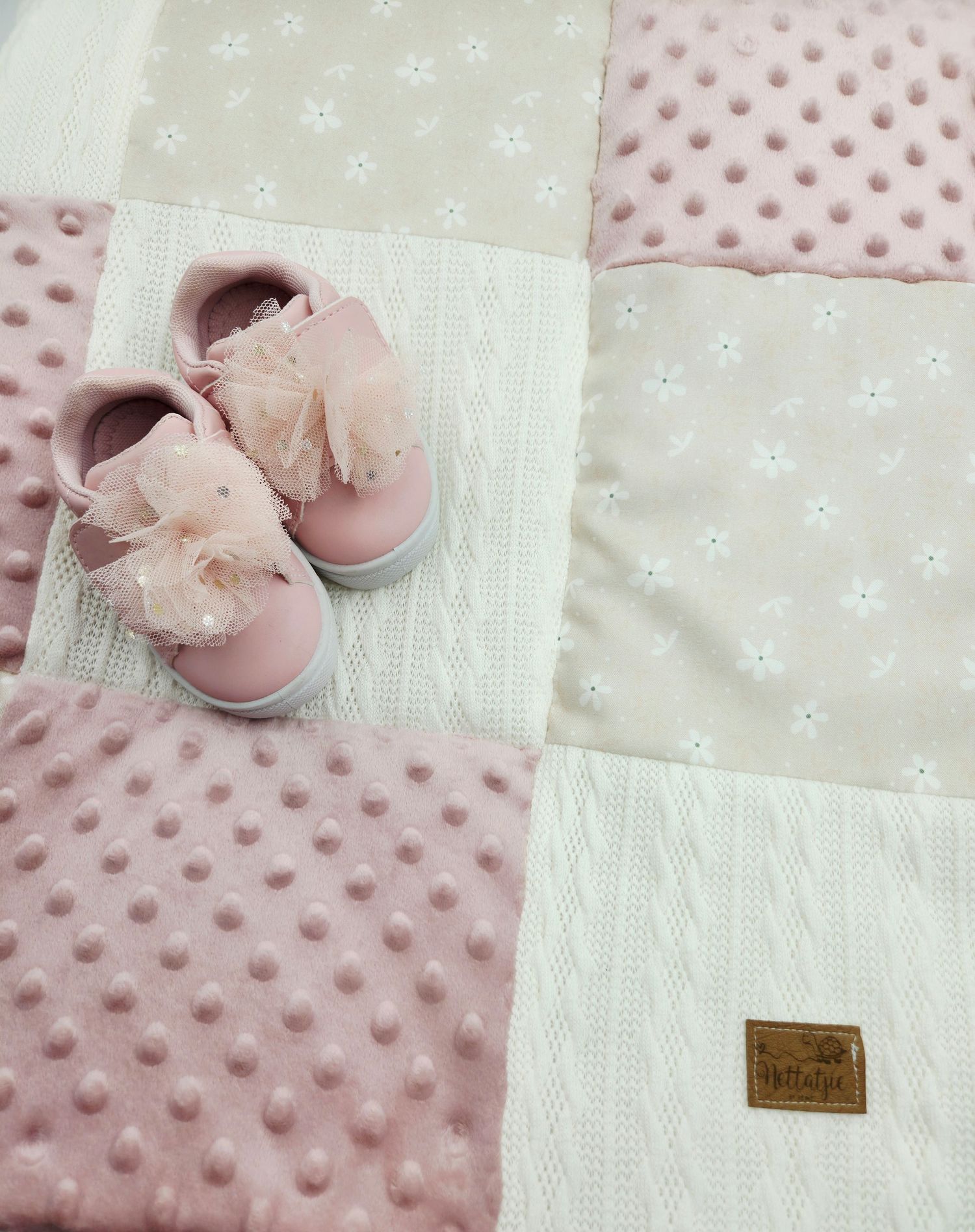 Delicate pink and cream baby blanket with bow-adorned ballet shoes on textured minky fabric.