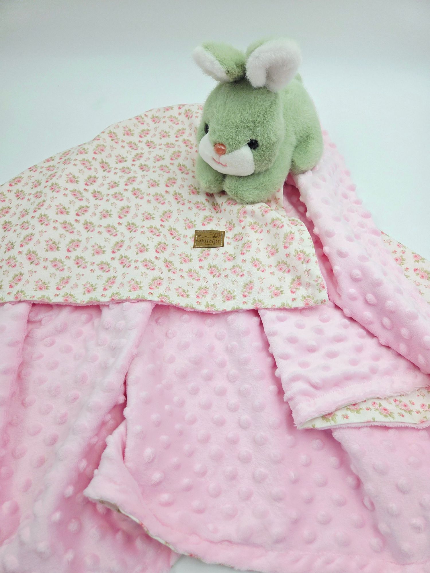 Pink minky dot baby blanket with floral print and green plush bunny.