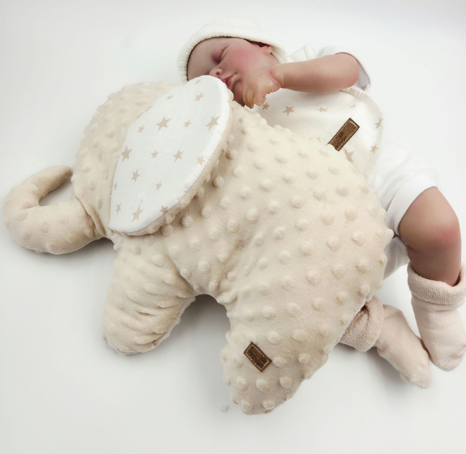 Plush cream colored baby accessories including minky blanket and stuffed toy on white surface.