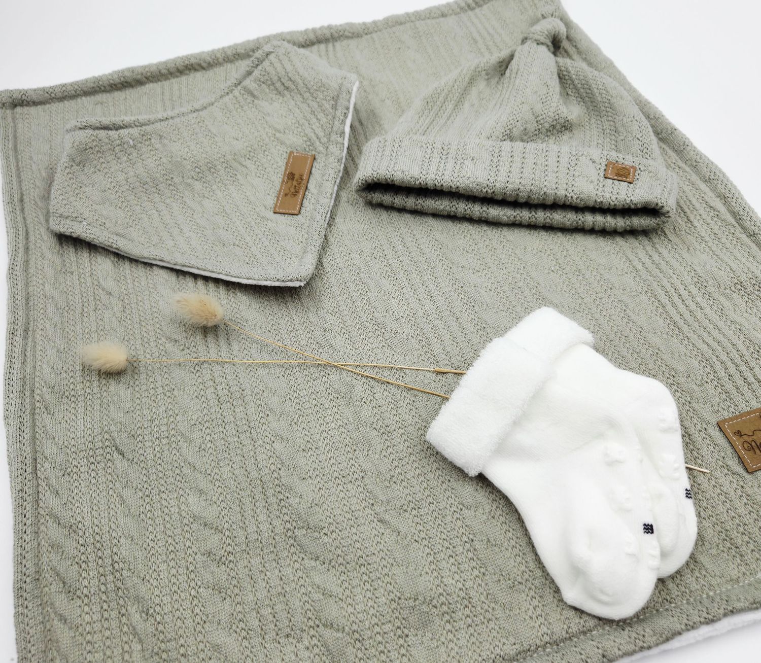 Gray cable knit baby blanket with white mittens and leather accents.