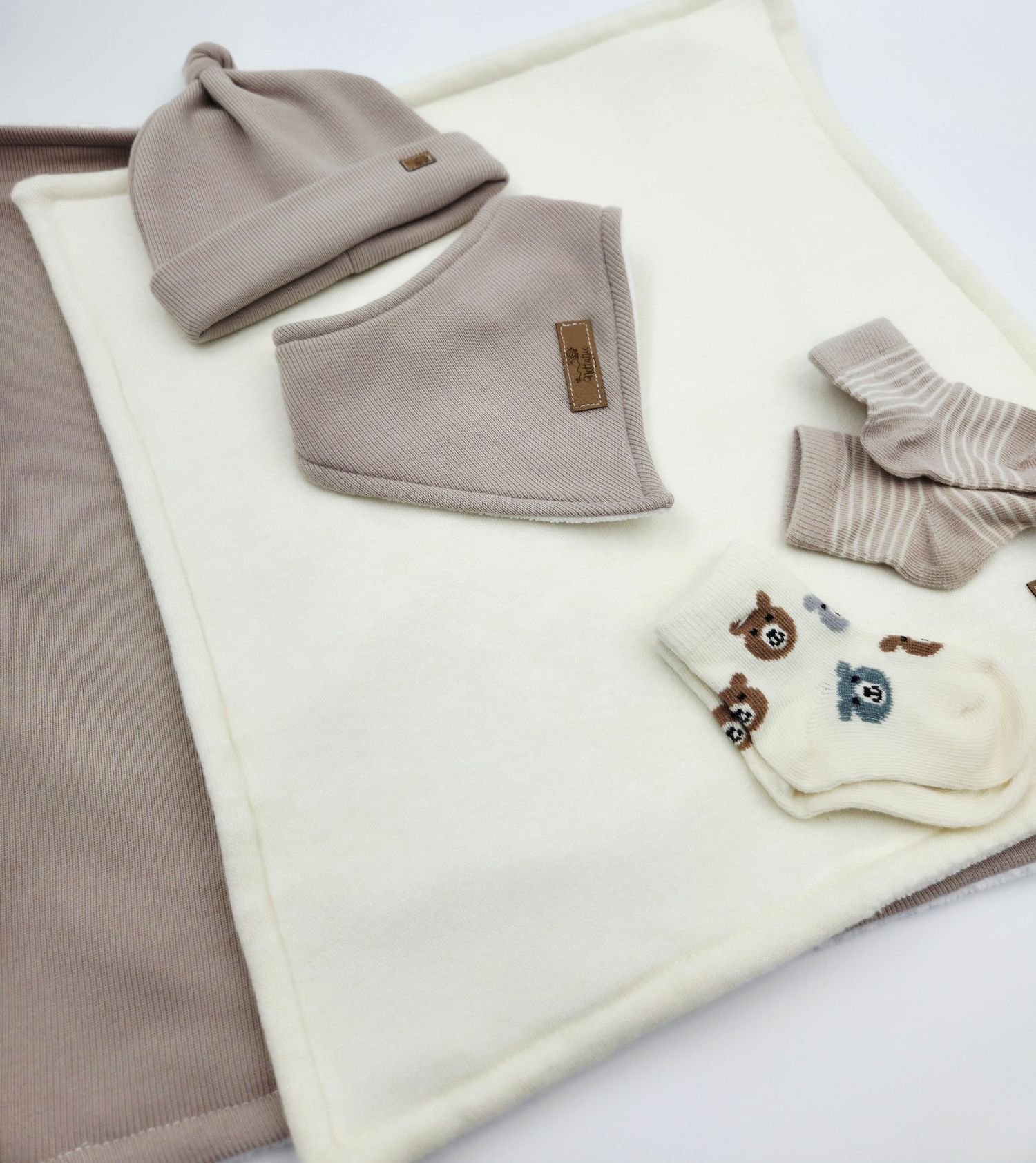 Neutral colored baby clothing set with small embroidered details.