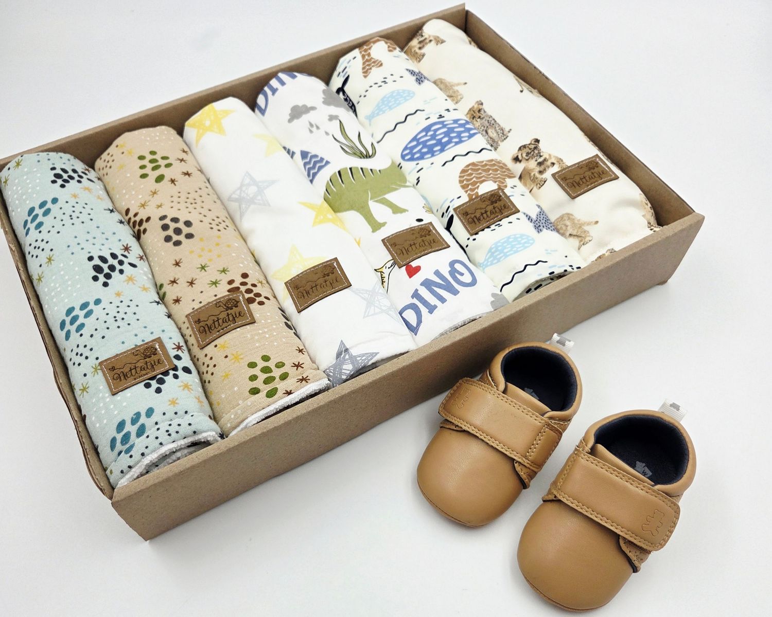 Boxed baby items including soft moccasins and patterned fabric with woodland animal designs.