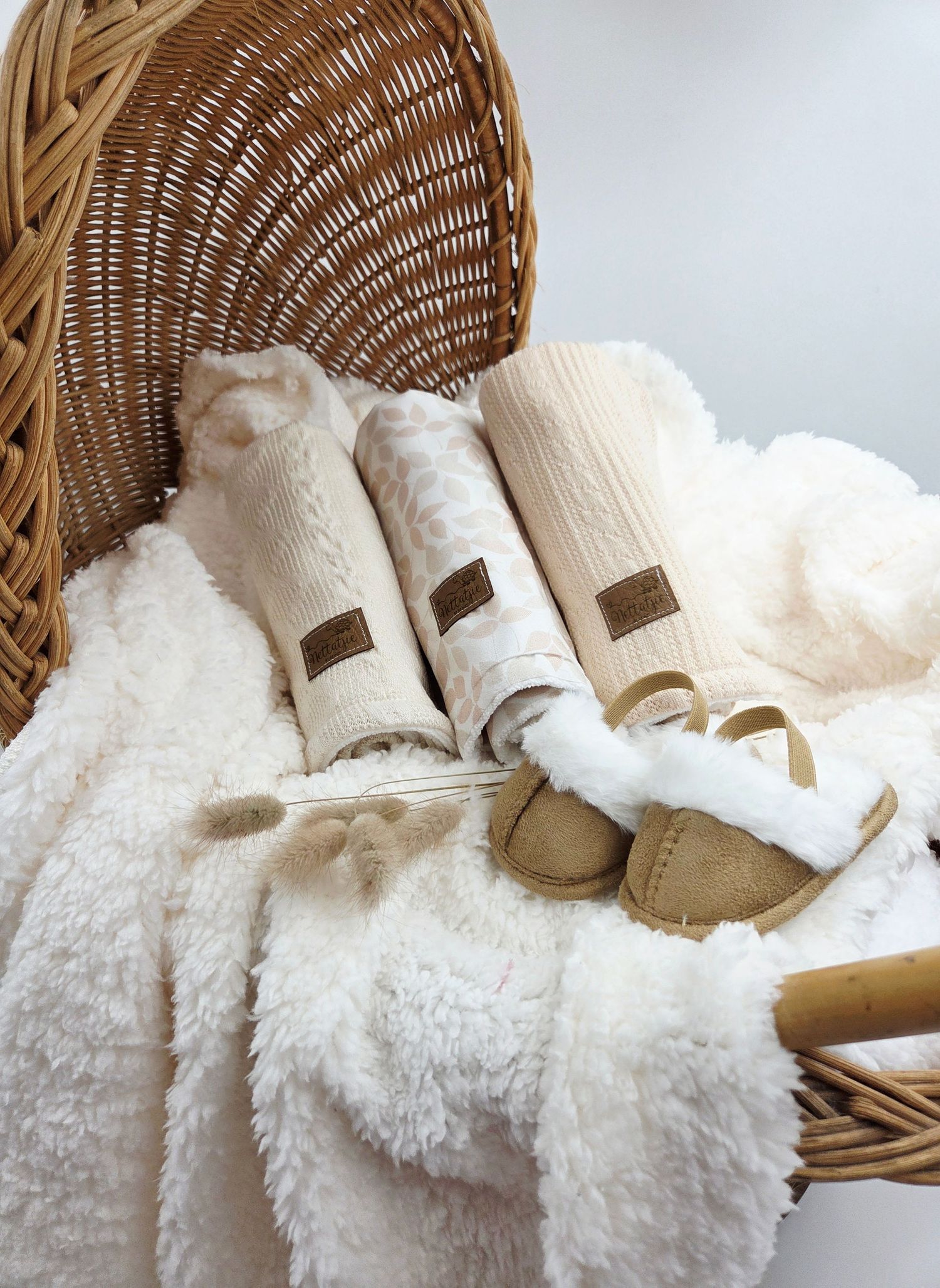Cozy white baby accessories and shoes arranged in wicker basket display.