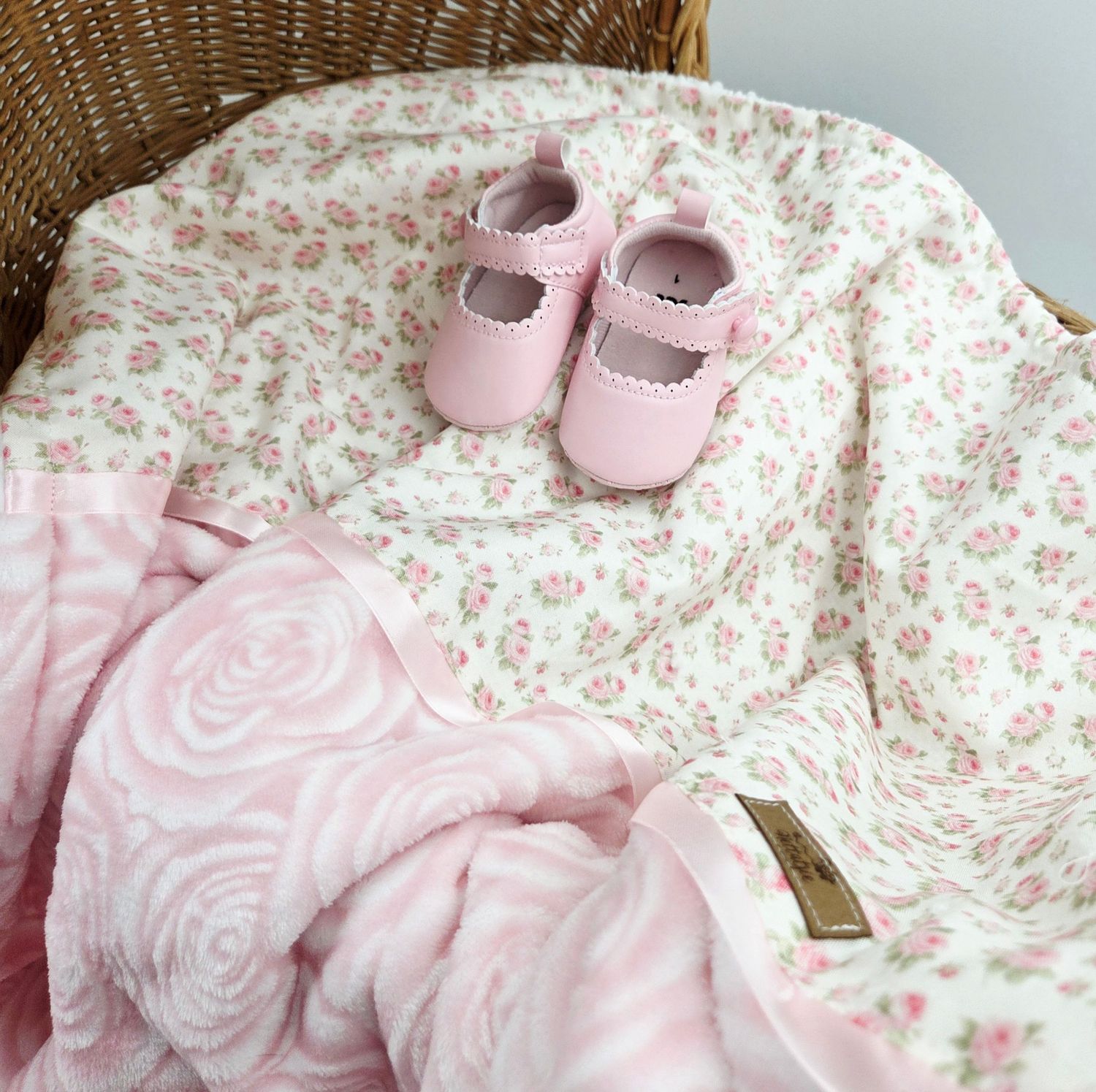 Pink floral baby blanket with matching shoes and delicate rose pattern details.