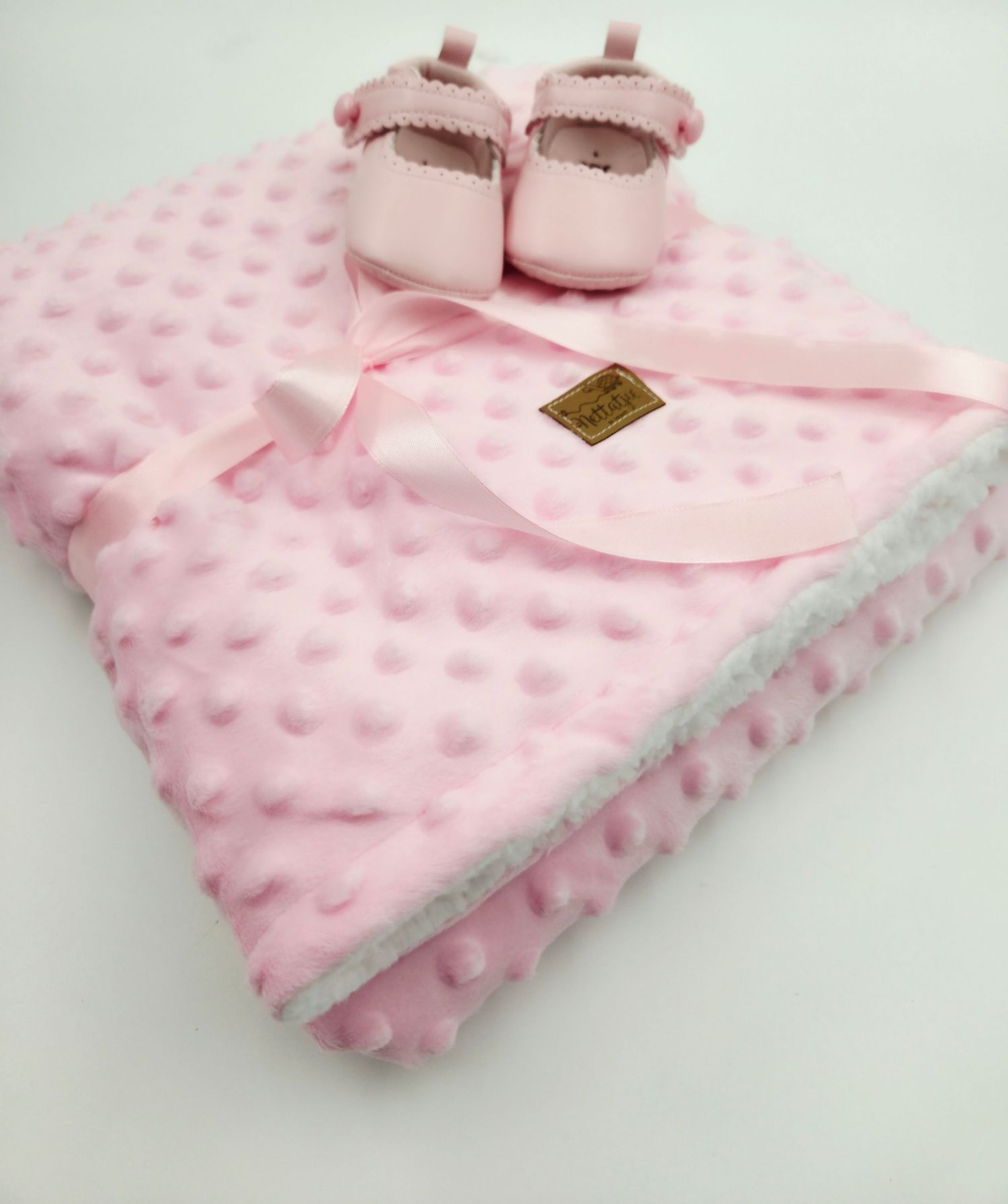 Textured pink baby blanket with minky dot pattern and small leather tag.