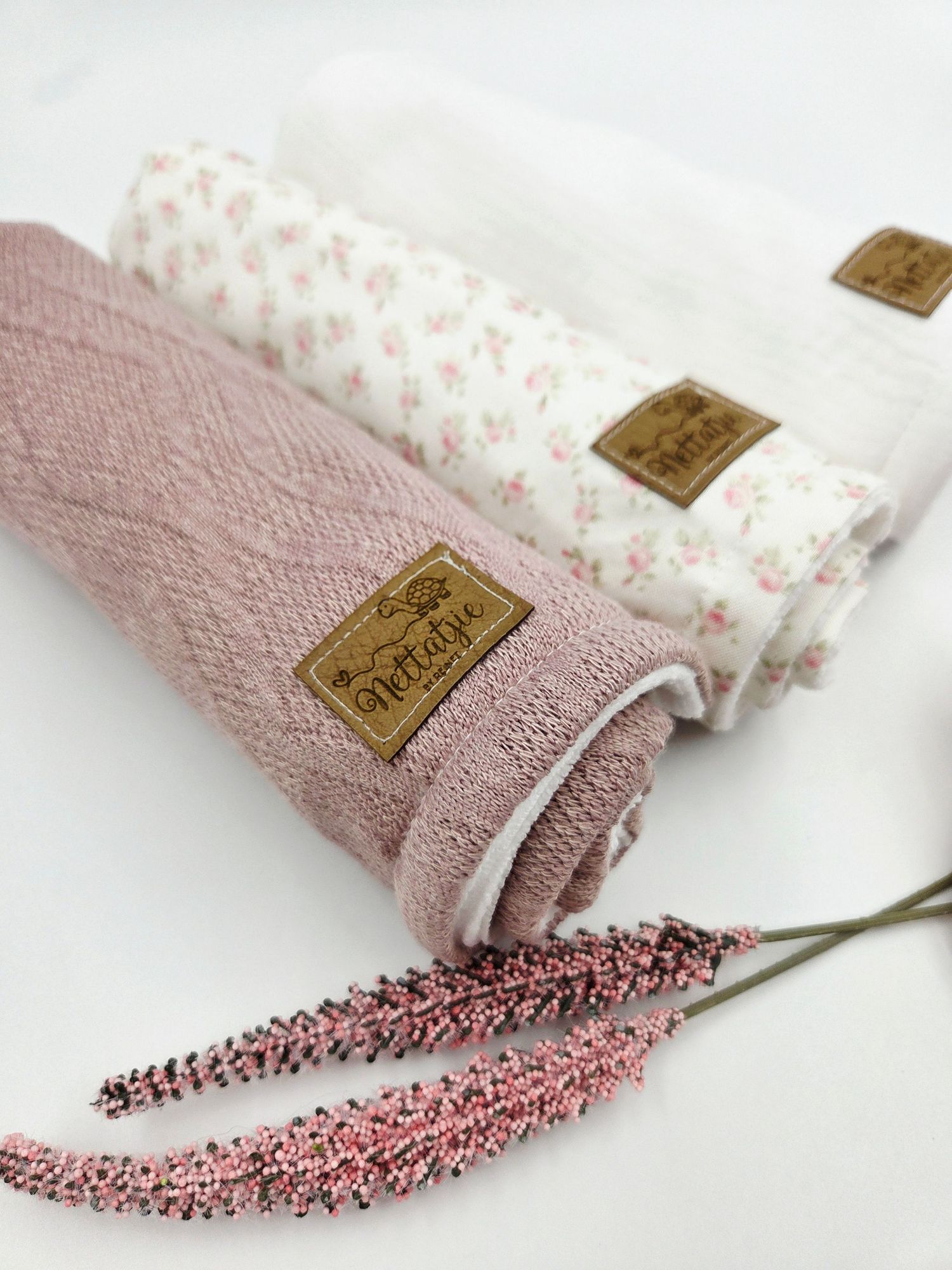 Rolled pink textured blankets with floral patterns and decorative gold labels.