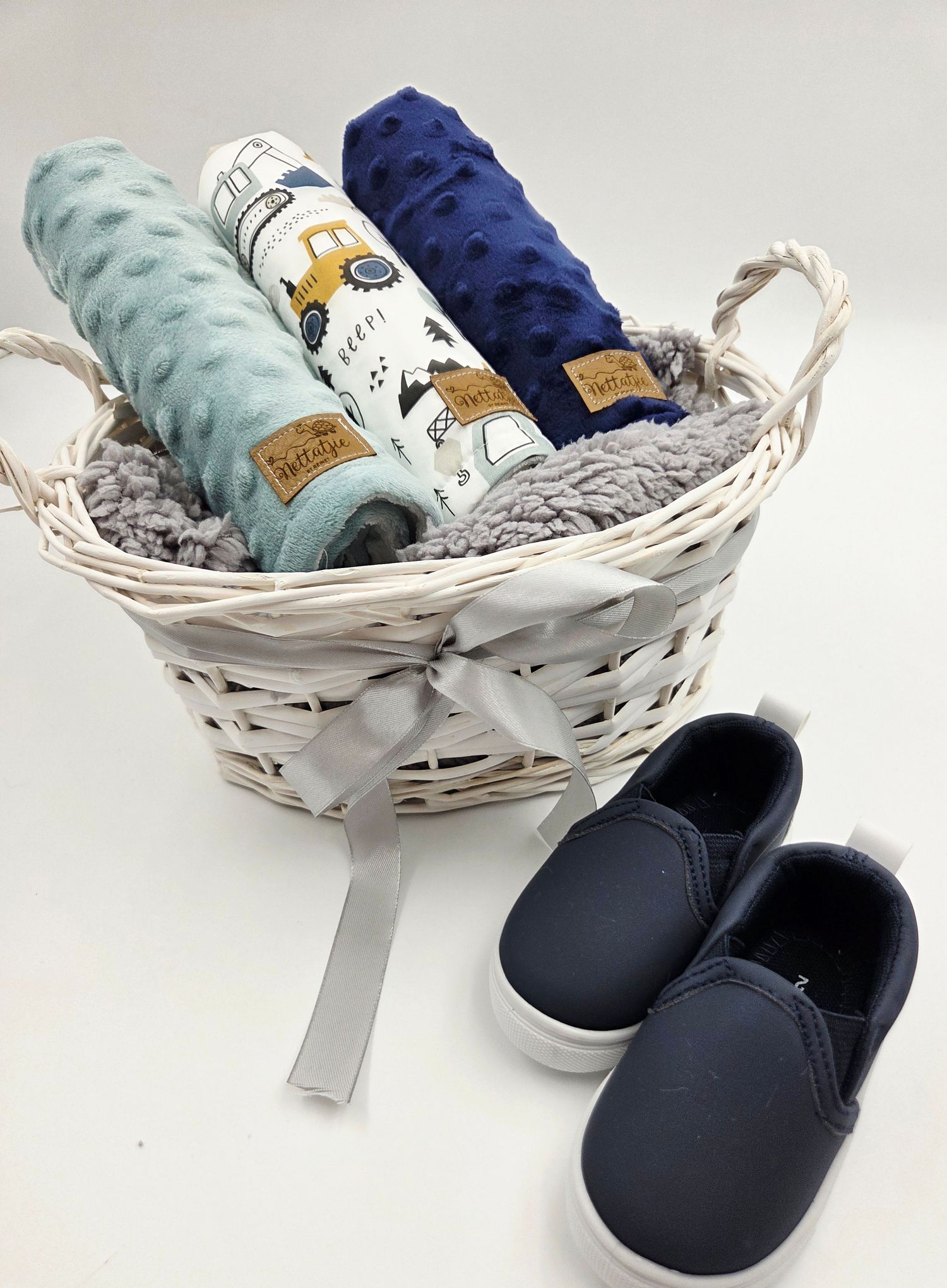 Navy and mint baby accessories with matching shoes displayed in white wicker basket.