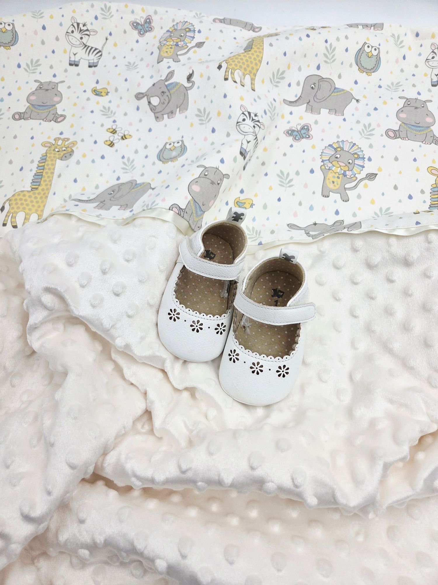White minky baby blanket with animal print pattern and matching shoes.