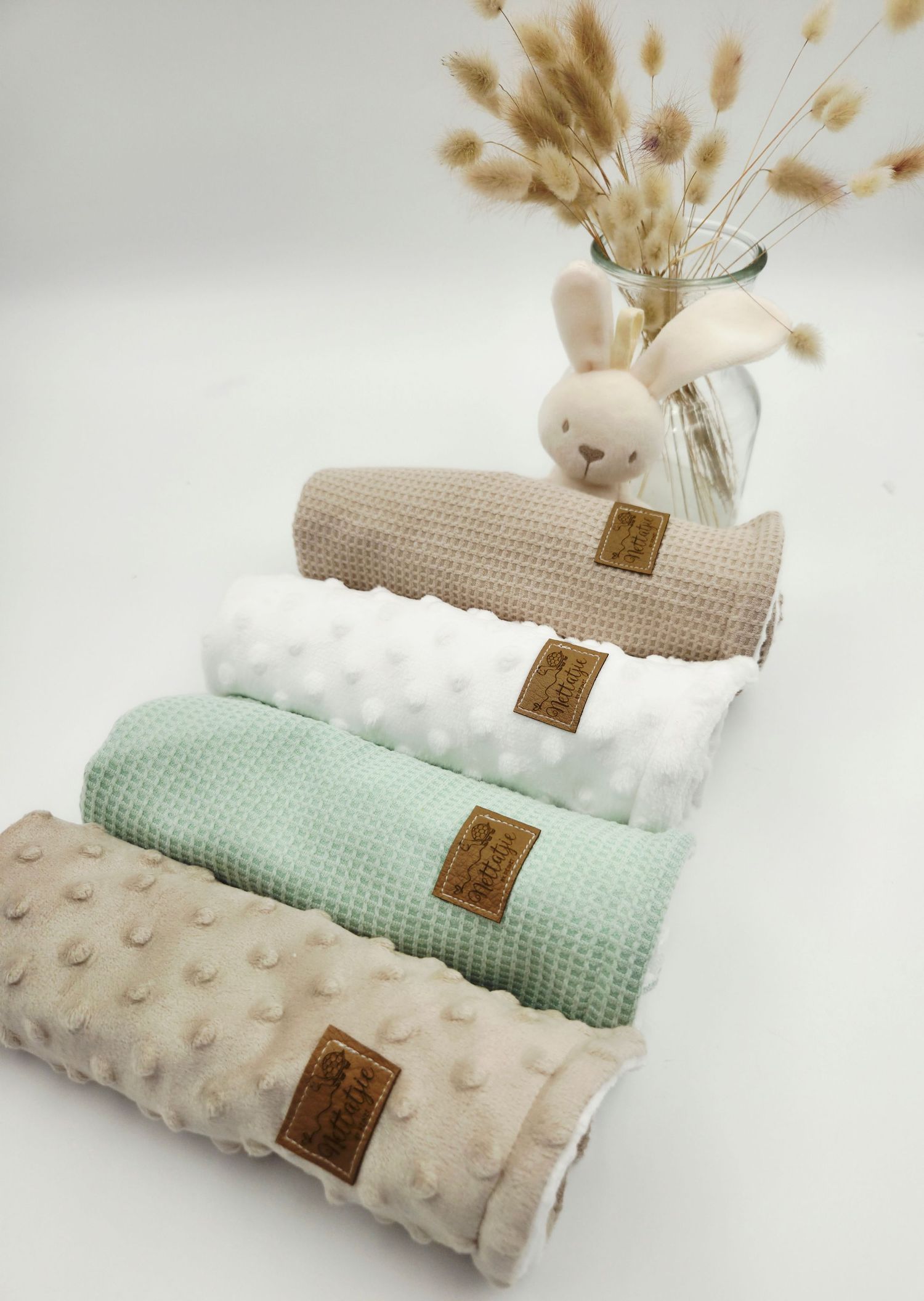 Soft textured baby blankets in mint green, beige and cream colors with minky dots arranged in a stylish display.