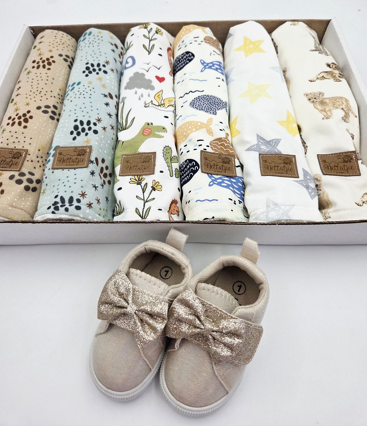Neutral colored baby shoes and patterned fabrics displayed in product photography sequence.