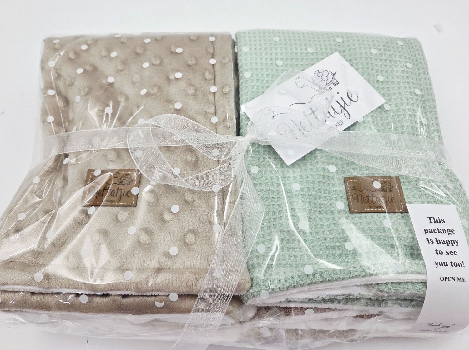 Neatly packaged baby blankets with leather tags wrapped in clear plastic packaging.