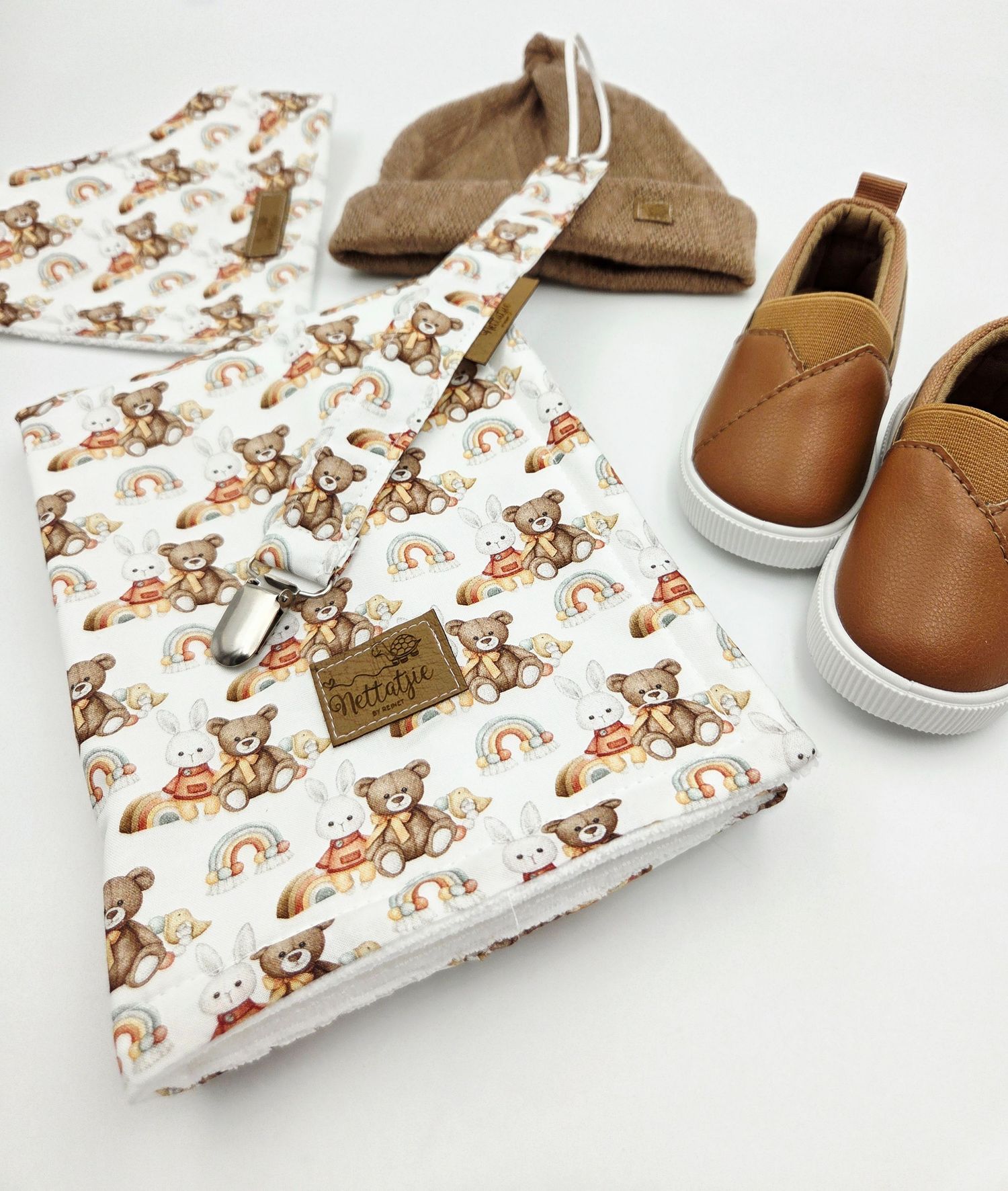 Baby blanket with brown teddy bear print pattern displayed with matching leather shoes.