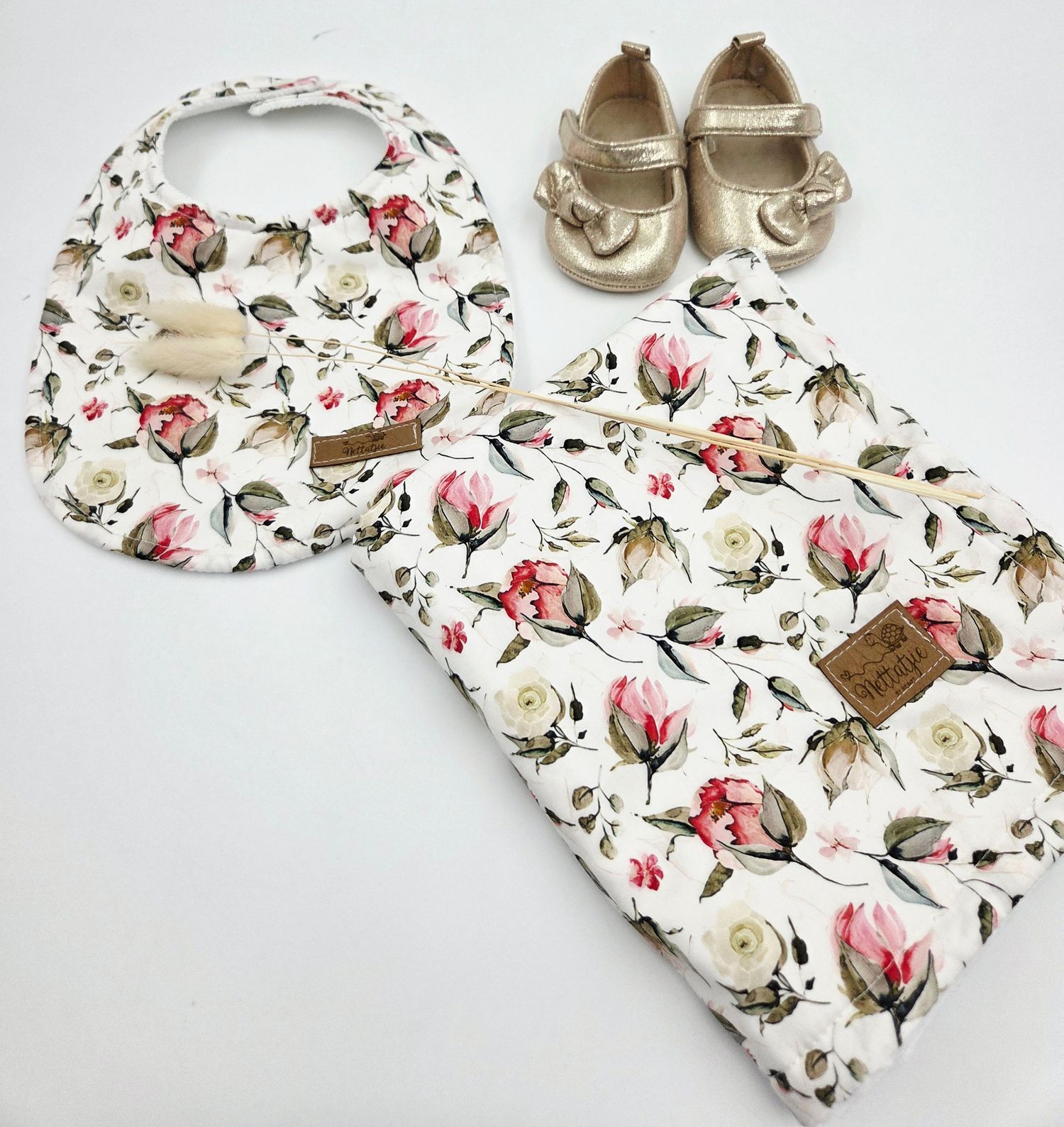 Floral print baby accessories and leather moccasins in cream and pink tones.