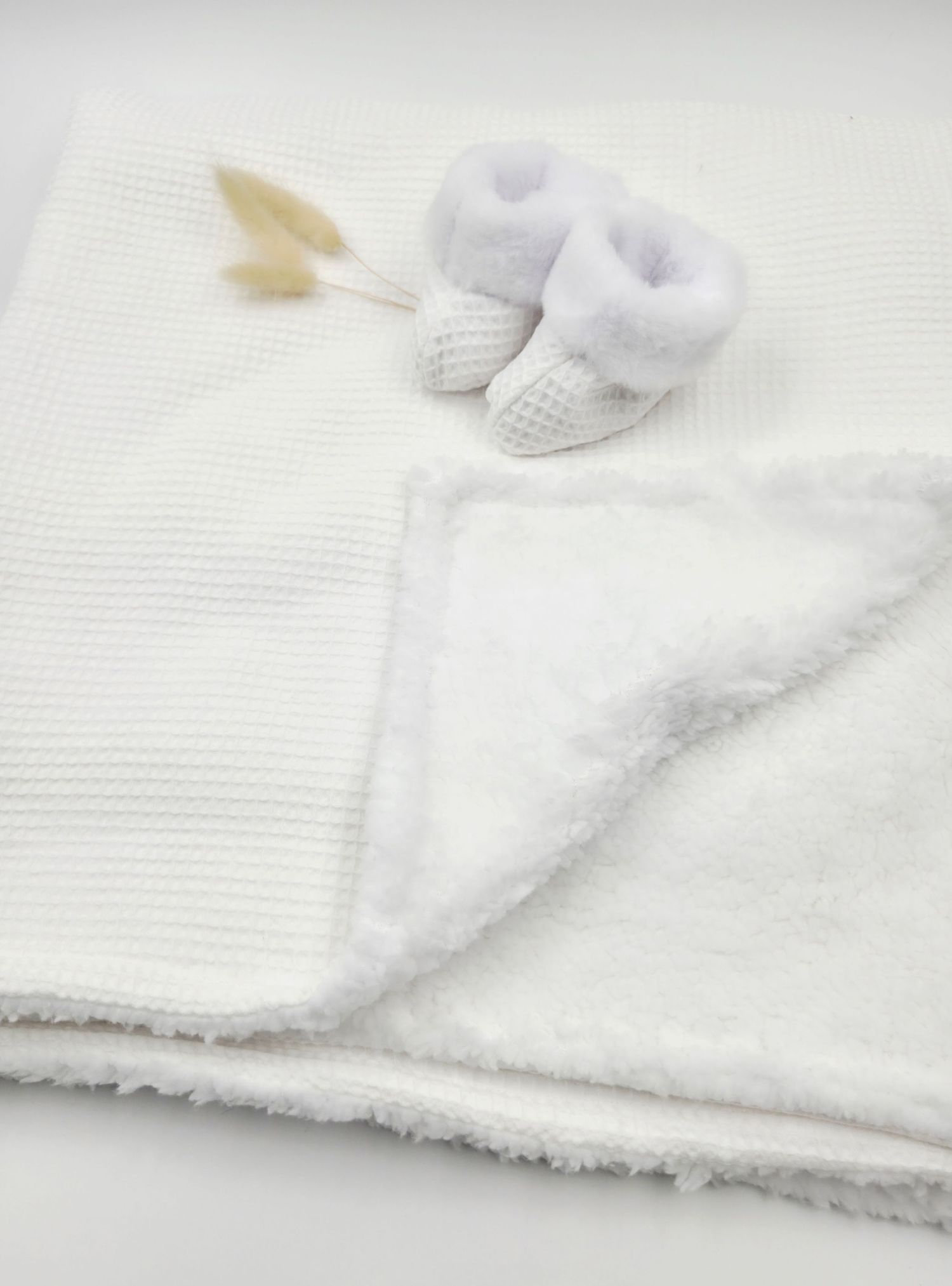 White knit baby blanket with sherpa lining and matching white booties, perfect for newborns.