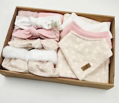 A gift box filled with pink and white baby headbands and floral bibs, perfect for a newborn girl.