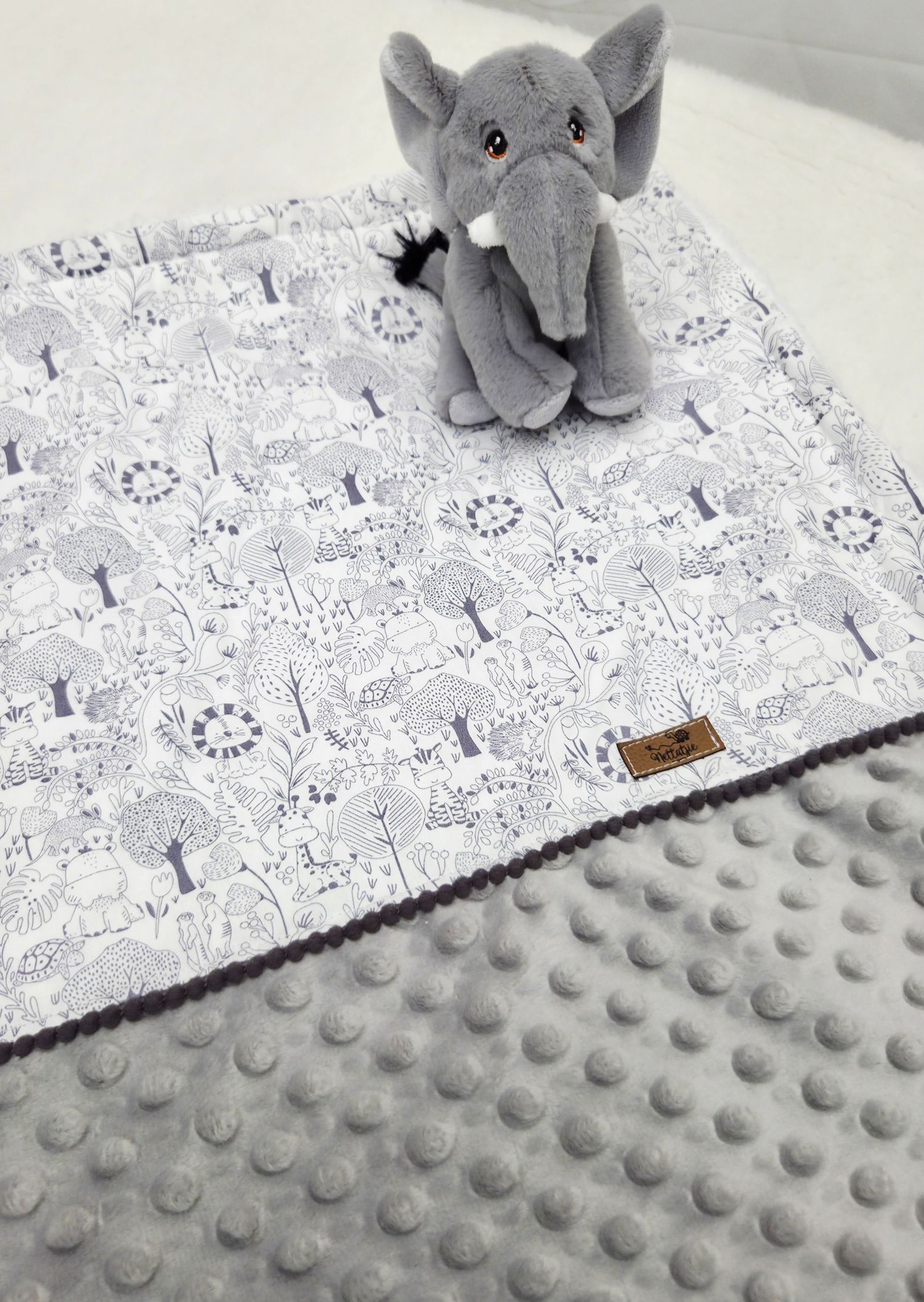 Gray minky dot baby blanket with woodland animal print fabric and a plush gray elephant stuffed toy.