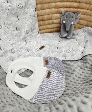 Baby set with elephant stuffed animal, white minky blanket, and patterned bib on wicker basket background.