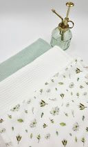 Soft floral print fabric with green botanical motifs beside sage green and white waffle-weave textiles on white background.