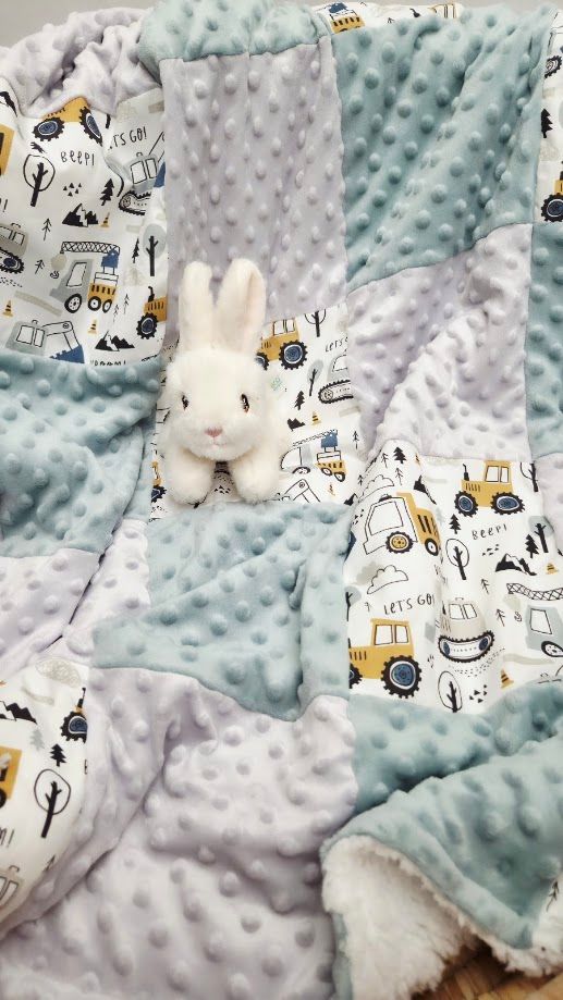 Soft baby quilt with vehicle print and minky dot fabric in blue and gray, with a white plush bunny stuffed animal.