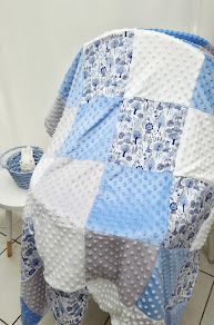 Blue and gray patchwork baby quilt with floral and polka dot fabric squares draped over a white chair.