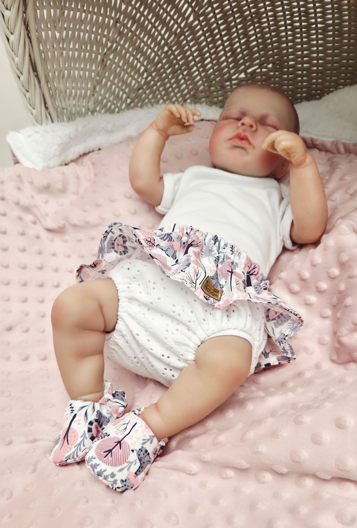 Sleeping baby in floral ruffle bloomers and matching shoes on a pink minky dot blanket.