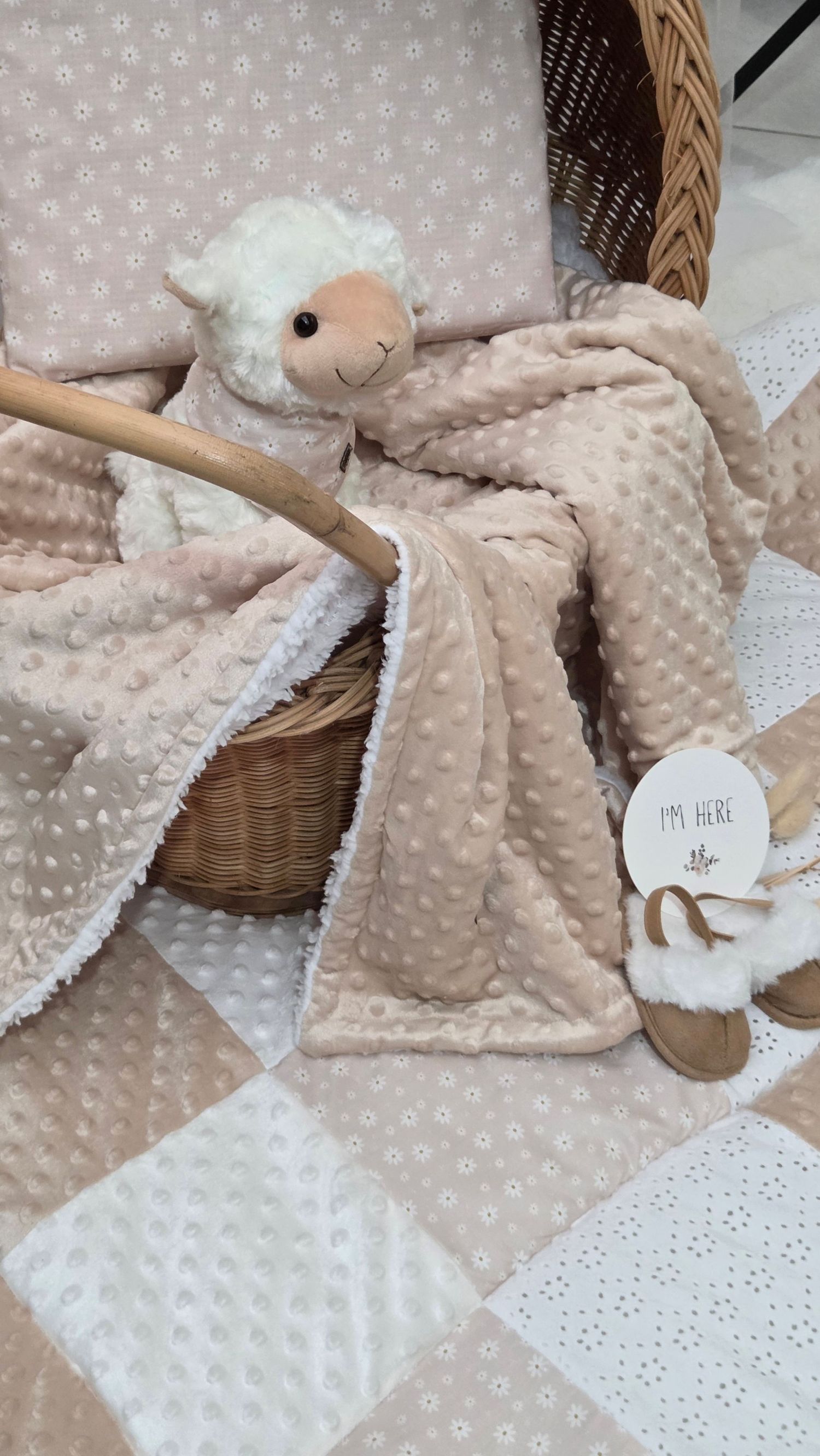 Soft pink minky dot baby blanket with lamb plush toy in a wicker basket on a floral quilt.