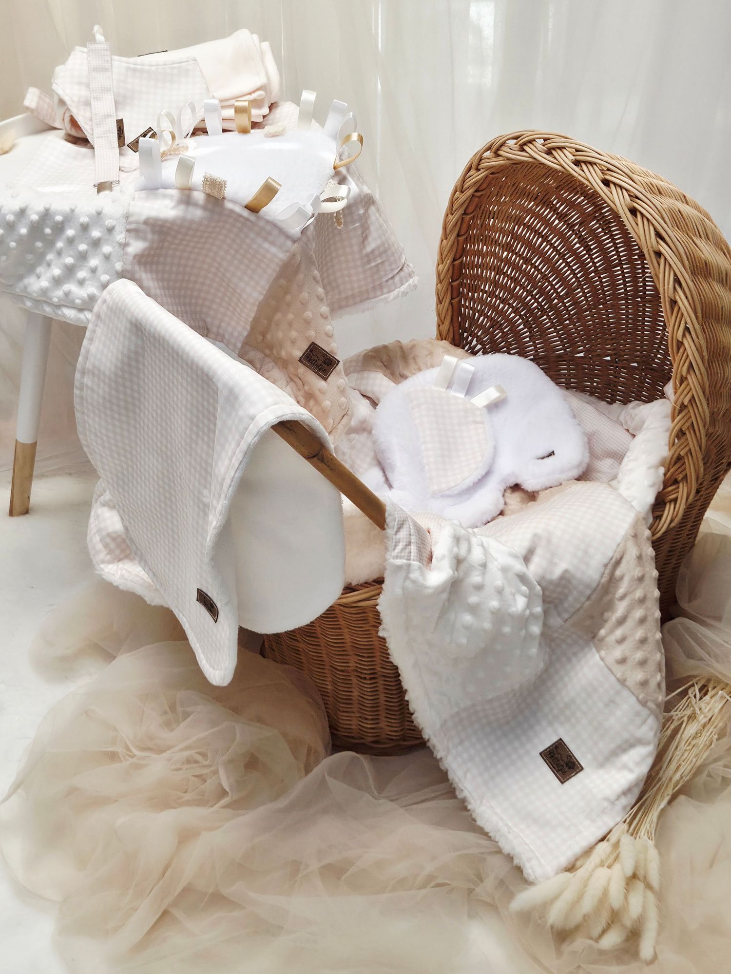 Cozy baby nursery setup with wicker bassinet, white waffle blankets, and soft plush toys in neutral tones.