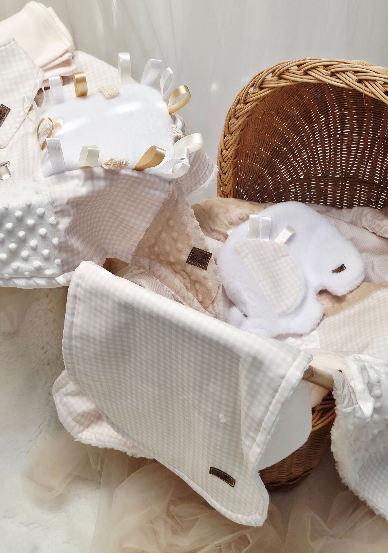Elegant baby gift basket with white waffle blanket, mittens, and soft pink accessories in a wicker Moses basket.