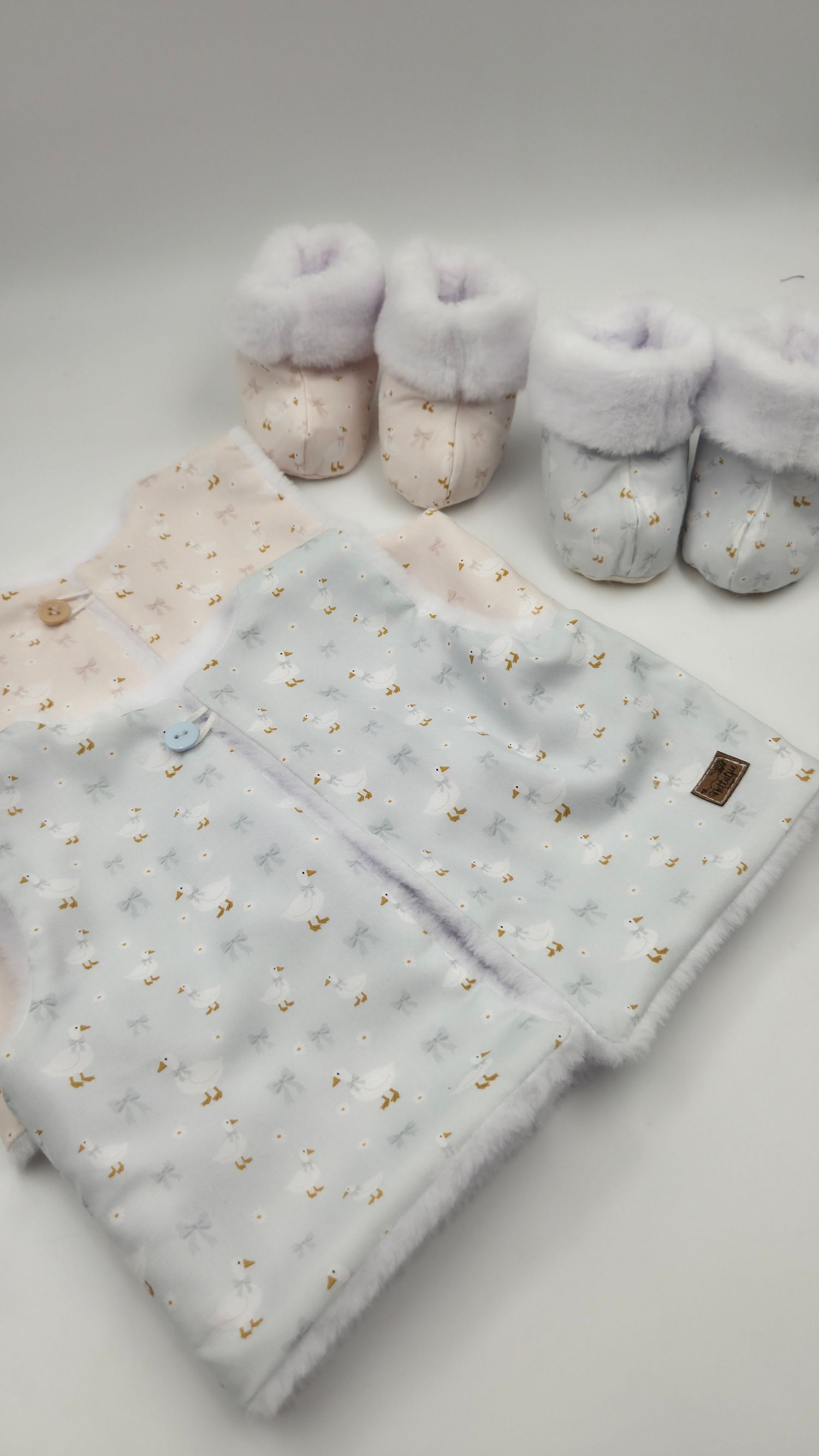 Soft baby gift set featuring a white floral blanket and matching fur-trimmed booties on a white background.