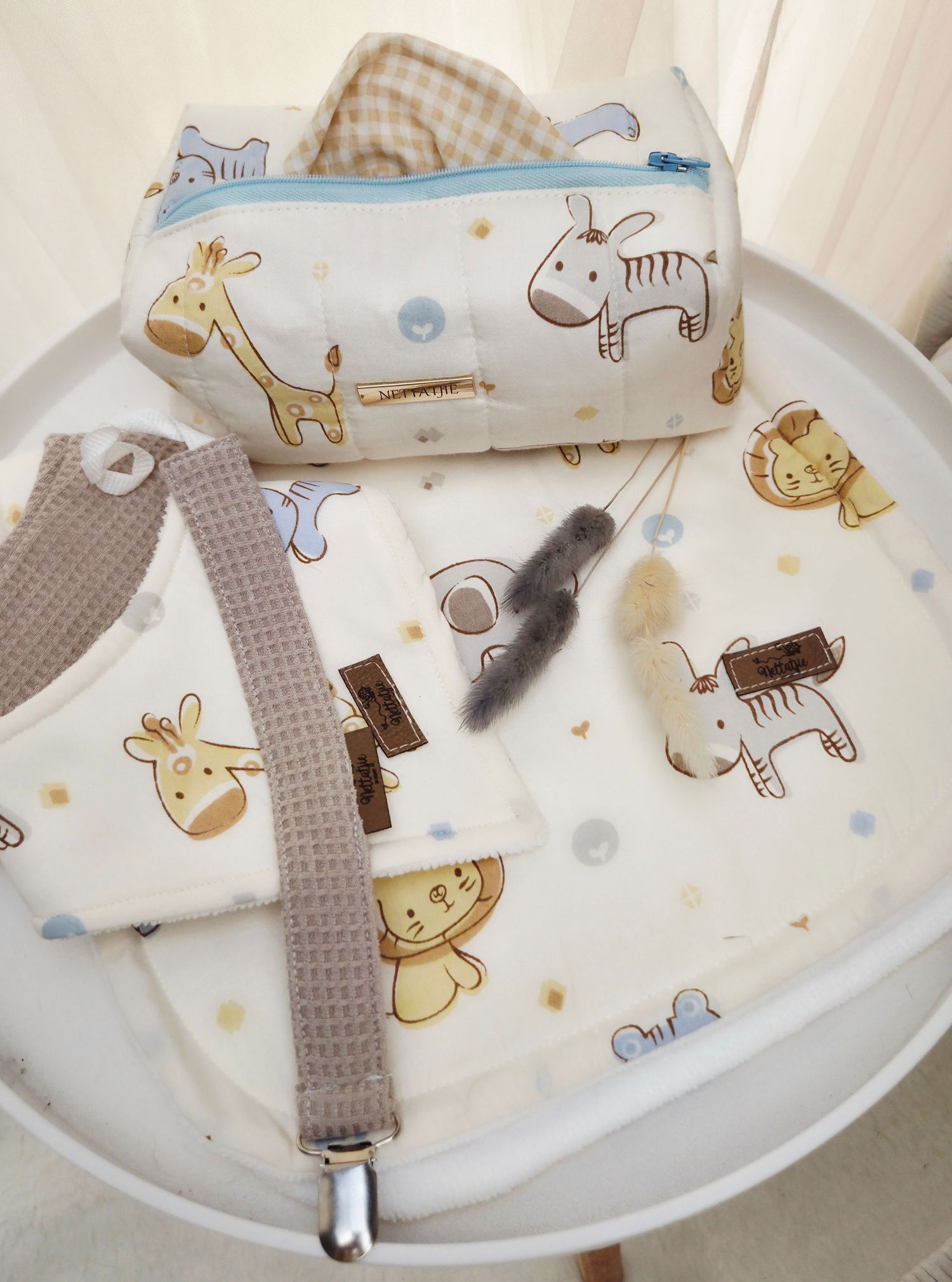 Baby safari animal print diaper bag set with matching blanket, pacifier clip, and small pouch on white tray.