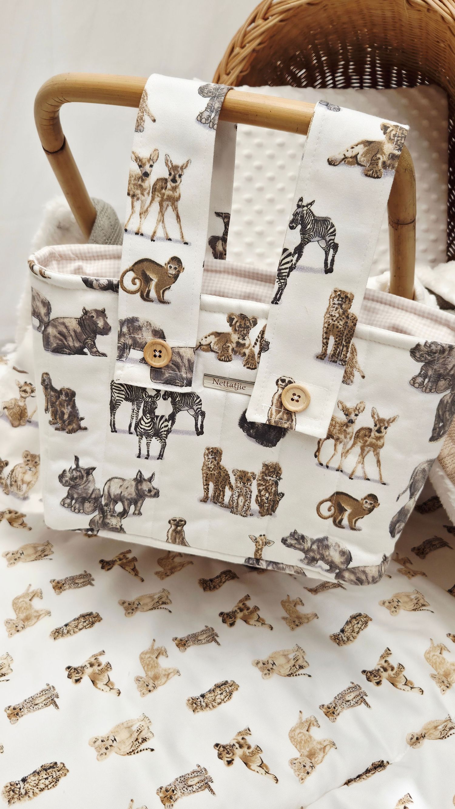 White fabric tote bag and blanket featuring safari animal print with zebras, deer, and leopards, displayed in a wicker basket.