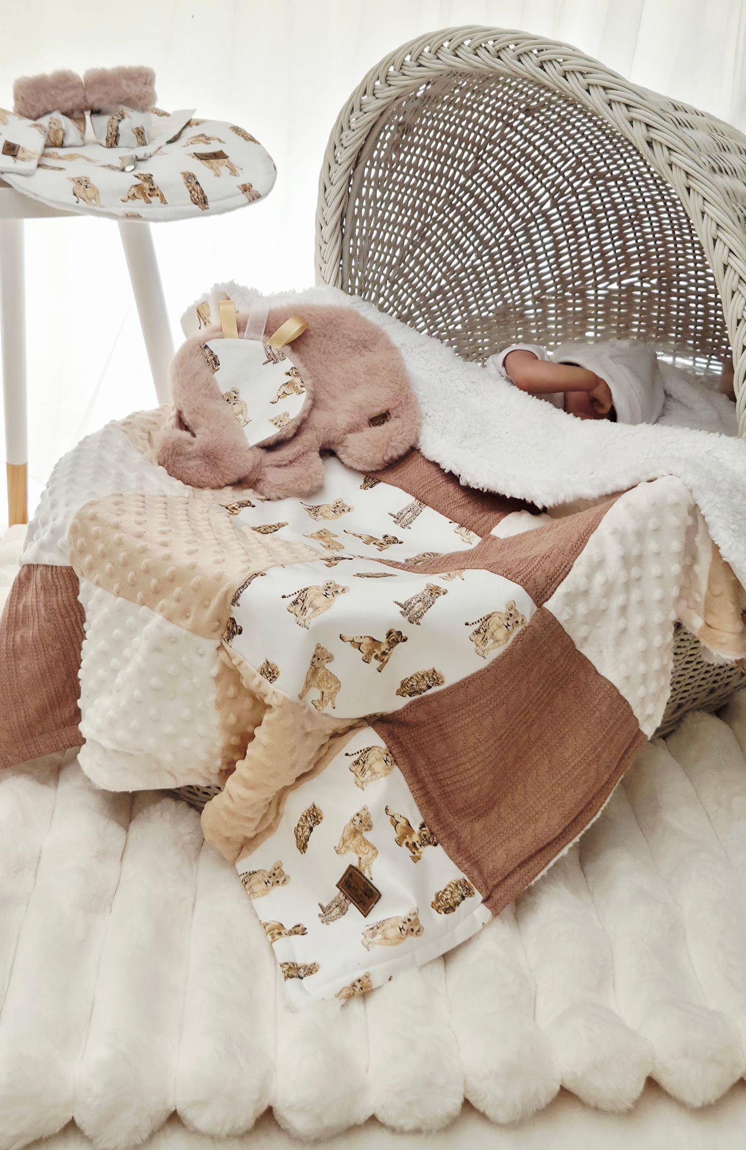 Cozy baby nursery setup with a wicker bassinet, minky patchwork blanket featuring deer print, and plush stuffed animal toys.
