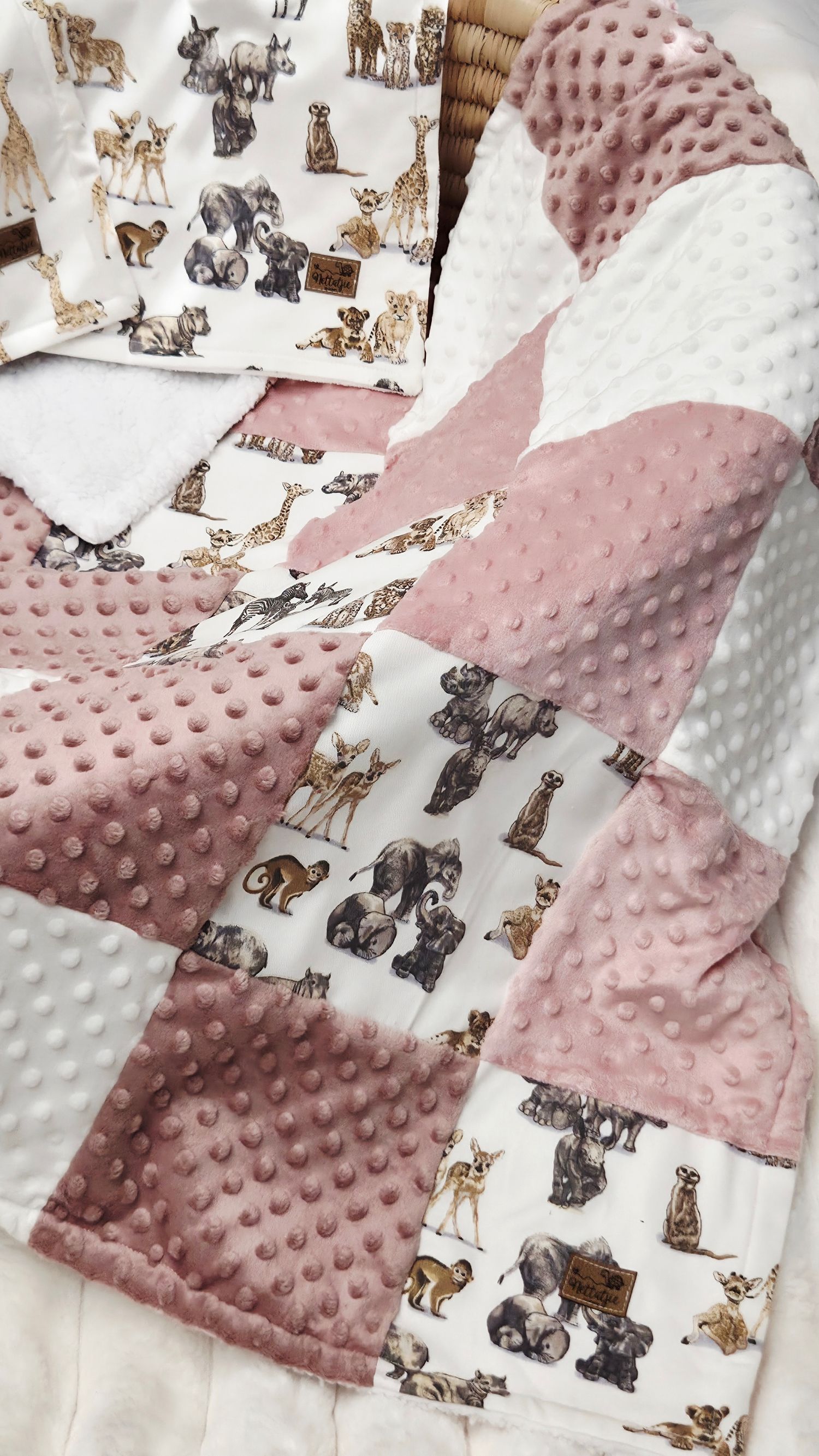Handmade patchwork baby blanket with pink minky dot fabric and safari animal print squares.