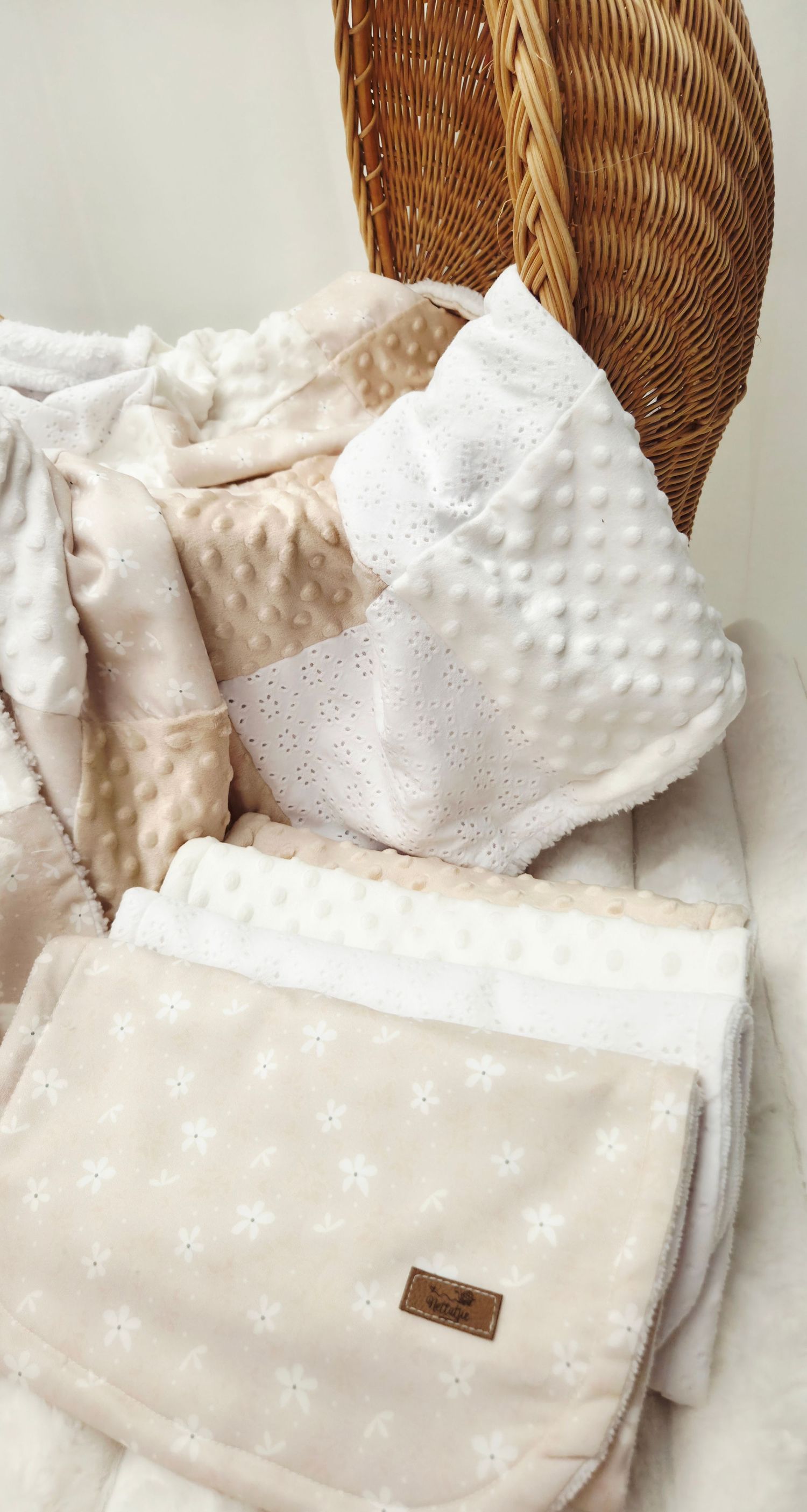 Soft beige and white minky dot baby blankets with floral pattern folded in a wicker basket.