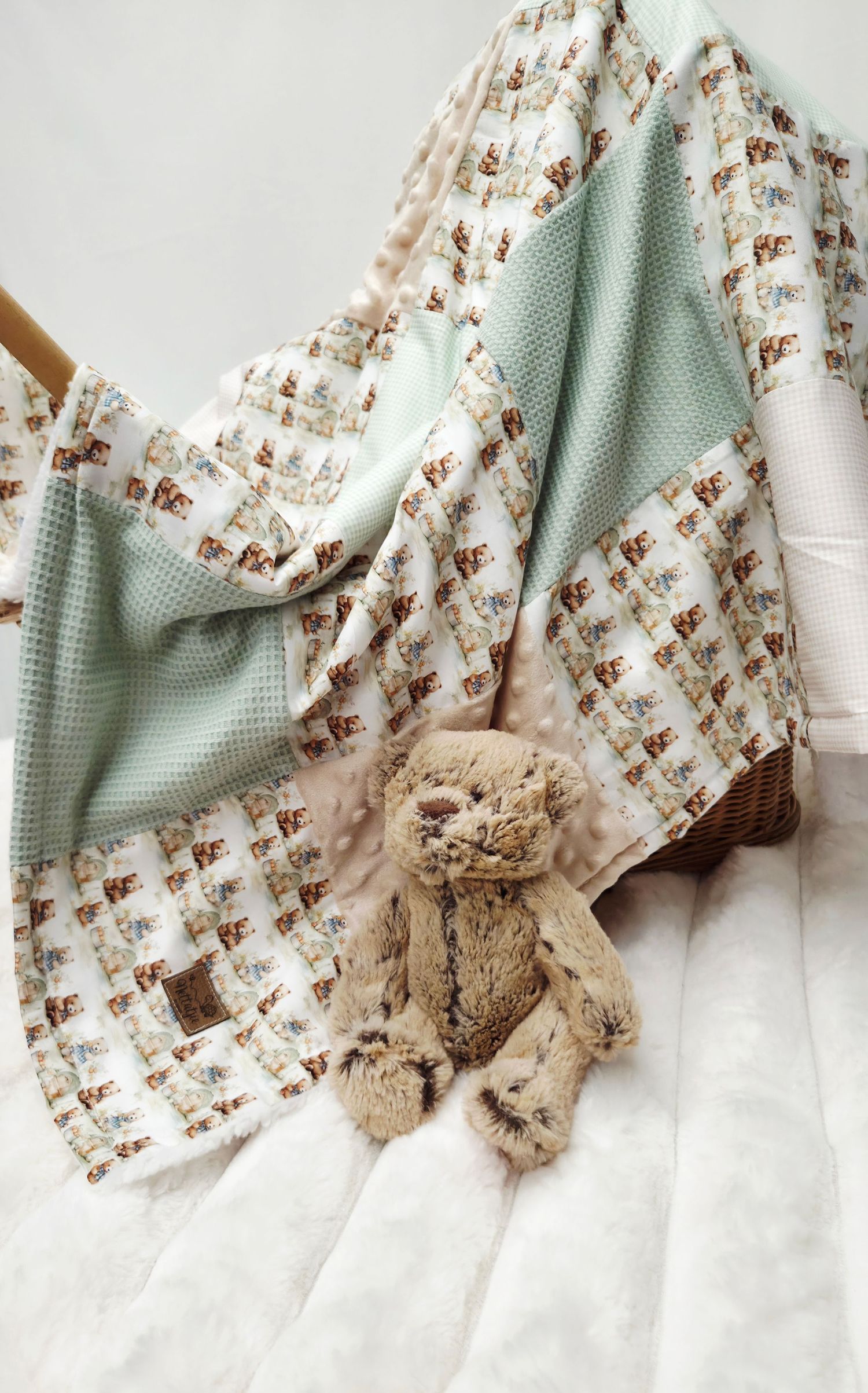 Soft baby quilt with woodland animal print in mint and white, displayed with a plush bunny toy.