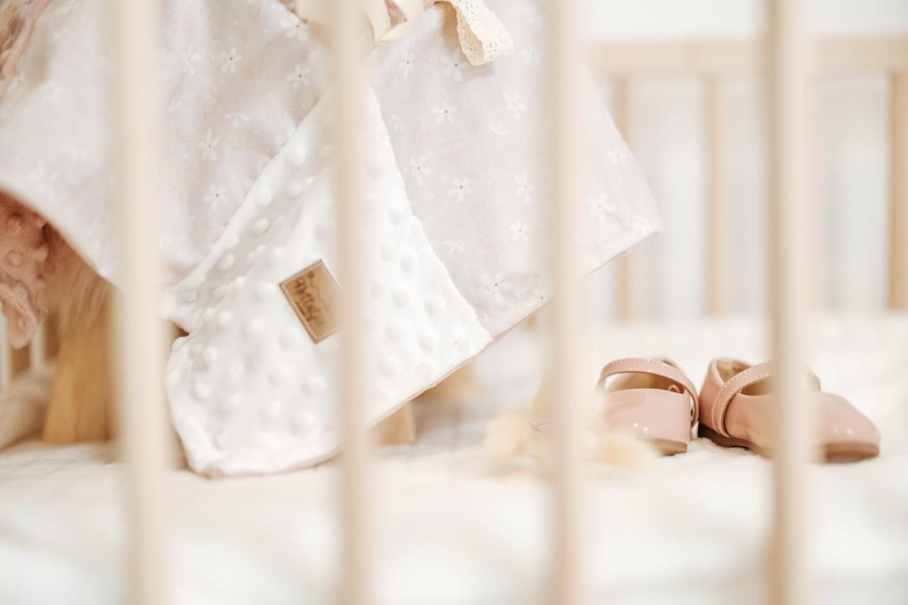 A delicate white lace wedding dress hangs elegantly against a light-colored background.