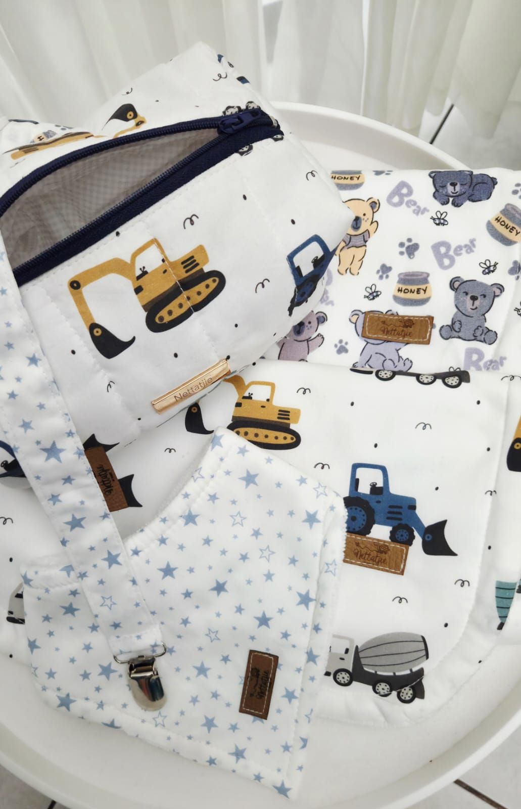 Baby boy nursery set with construction vehicles and teddy bear print fabric, featuring stars and trucks pattern.