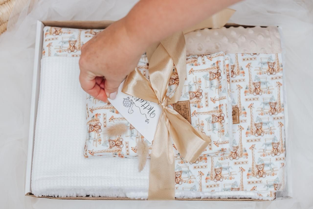 Hand unwrapping a gift box decorated with beige patterns and bow.