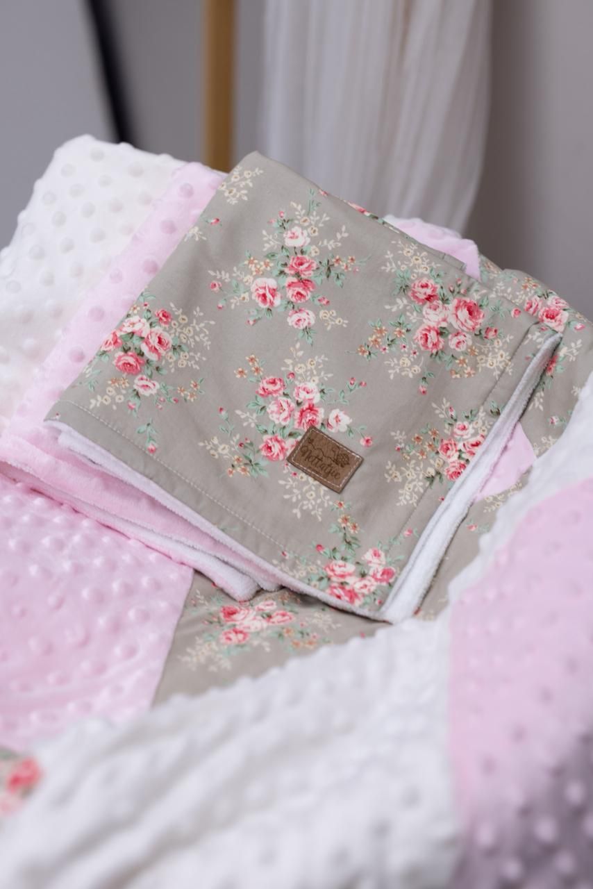Floral patterned gray fabric with pink roses lies against soft white minky material creating a cozy textile combination.