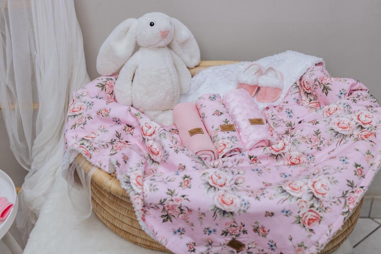 Cozy nursery bedding featuring pink floral patterns and a plush stuffed bunny on display.