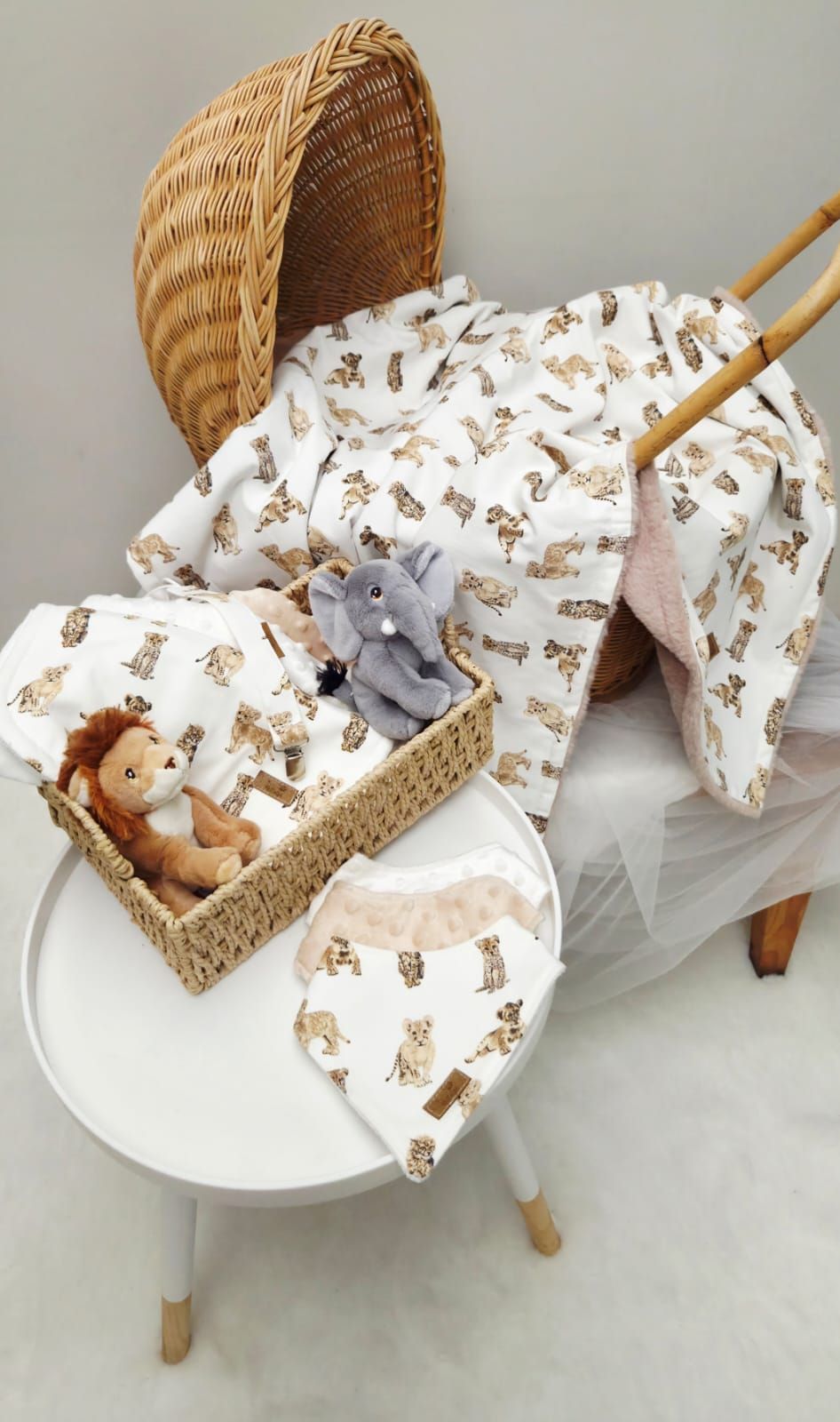 Woven basket with baby bedding featuring brown teddy bear print pattern and plush toys arranged in different positions.