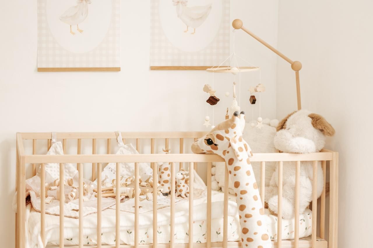 A cozy nursery room decorated in neutral tones with a wooden crib, plush toys, and soft lighting.