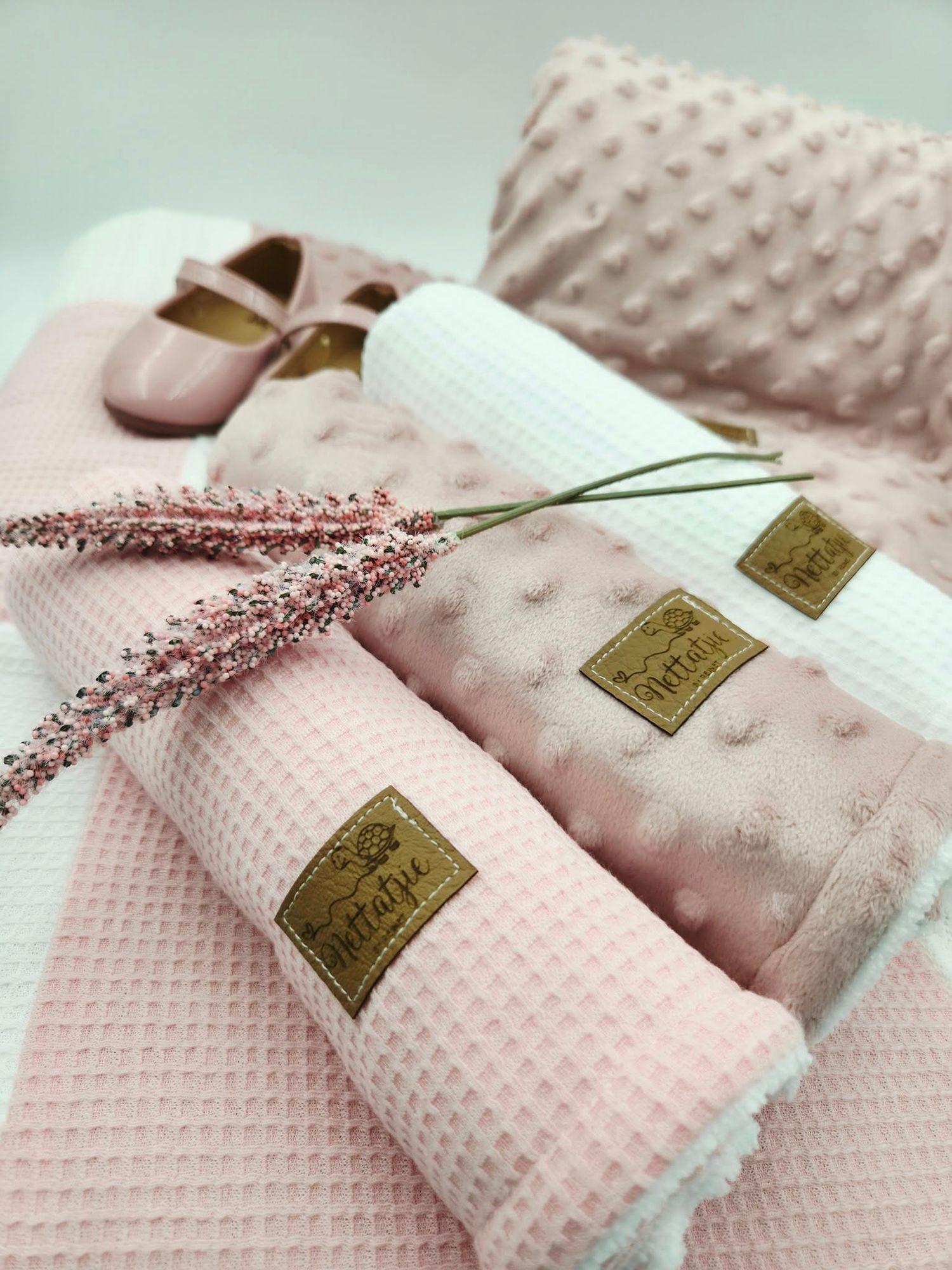 Pink textured minky blanket with gold label and decorative floral sprig.