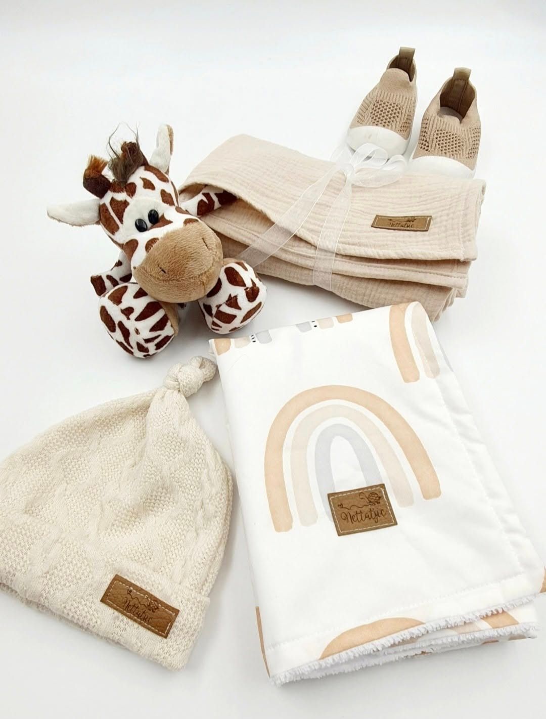 Neutral toned baby set with rainbow pattern blanket and knit accessories.