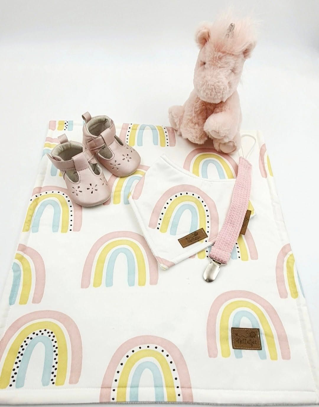 Baby blanket with pastel rainbow pattern and stuffed animal accessories.