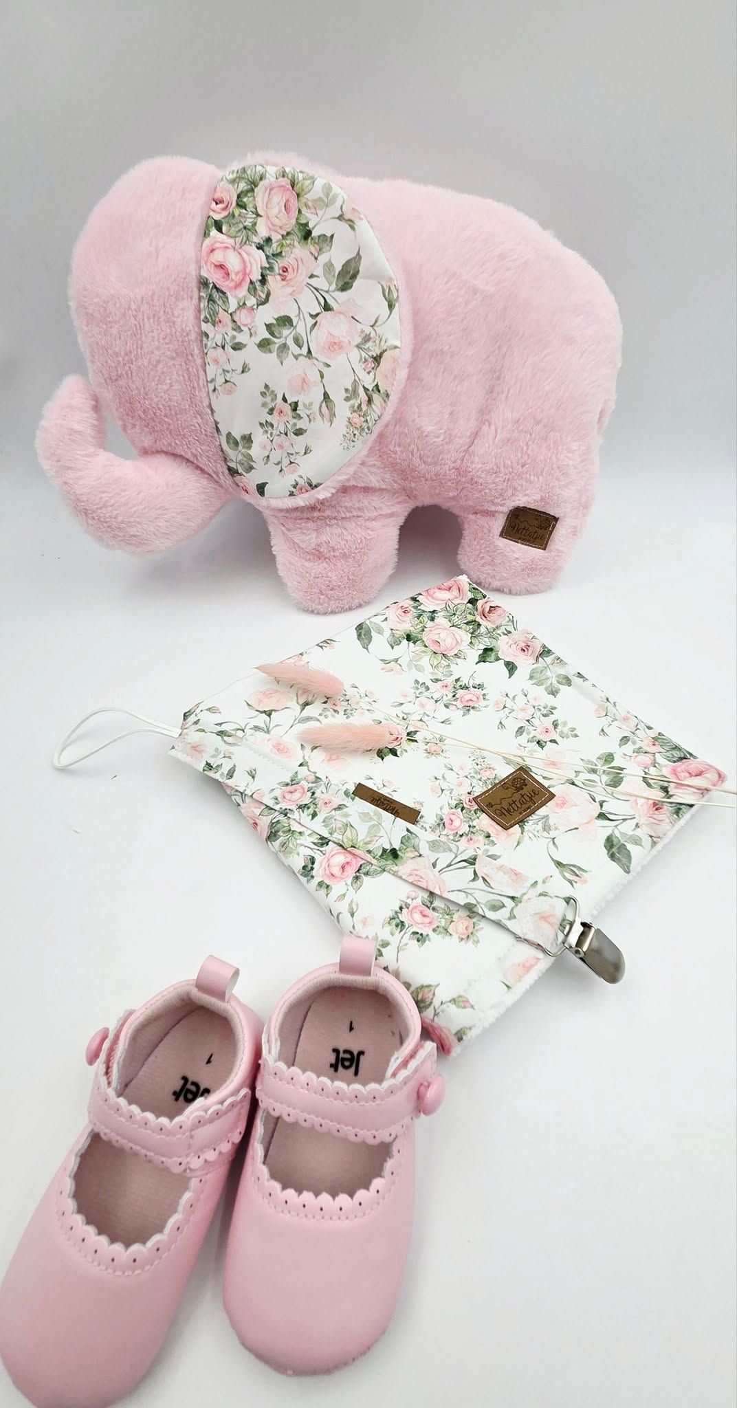 Pink nursery set featuring floral print blanket, cushion and matching shoes.